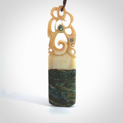 This is a large carved Manaia pendant. It is made from unique materials - New Zealand Obay Stone, Bone, Paua shell, Brass and Mother of Pearl. The face of the Manaia is carved with a traditional design in the front. It is carved front and back and has traditional carved designs. This is a large and very traditional pendant that is a collectors piece.