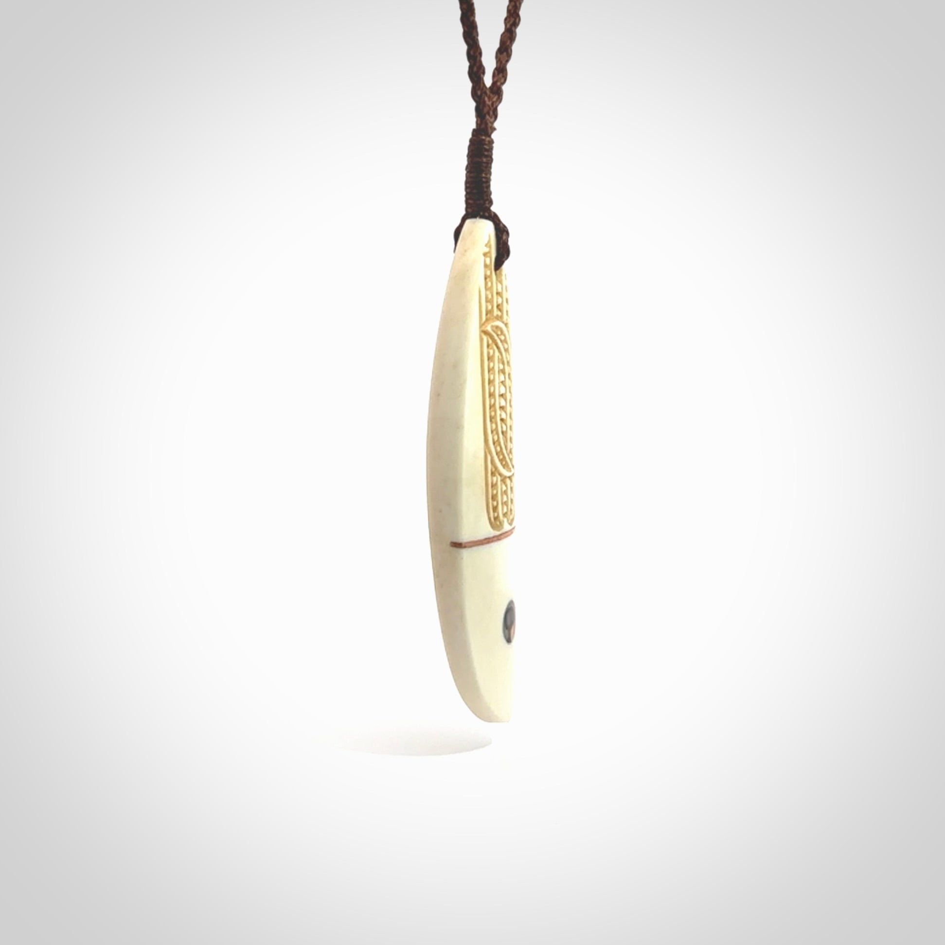 This is a wonderful, finely carved drop pendant. It is hand carved by Andrew Doughty and we will ship it to you free anywhere in the world. Hand made from bone with Paua shell and copper inlay. Delivered with an adjustable brown cord.