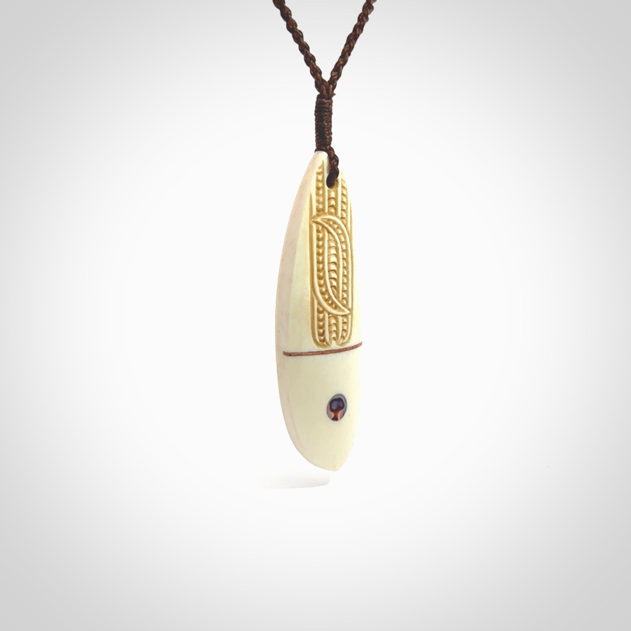 This is a wonderful, finely carved drop pendant. It is hand carved by Andrew Doughty and we will ship it to you free anywhere in the world. Hand made from bone with Paua shell and copper inlay. Delivered with an adjustable brown cord.