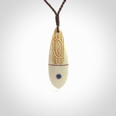 This is a wonderful, finely carved drop pendant. It is hand carved by Andrew Doughty and we will ship it to you free anywhere in the world. Hand made from bone with Paua shell and copper inlay. Delivered with an adjustable brown cord.