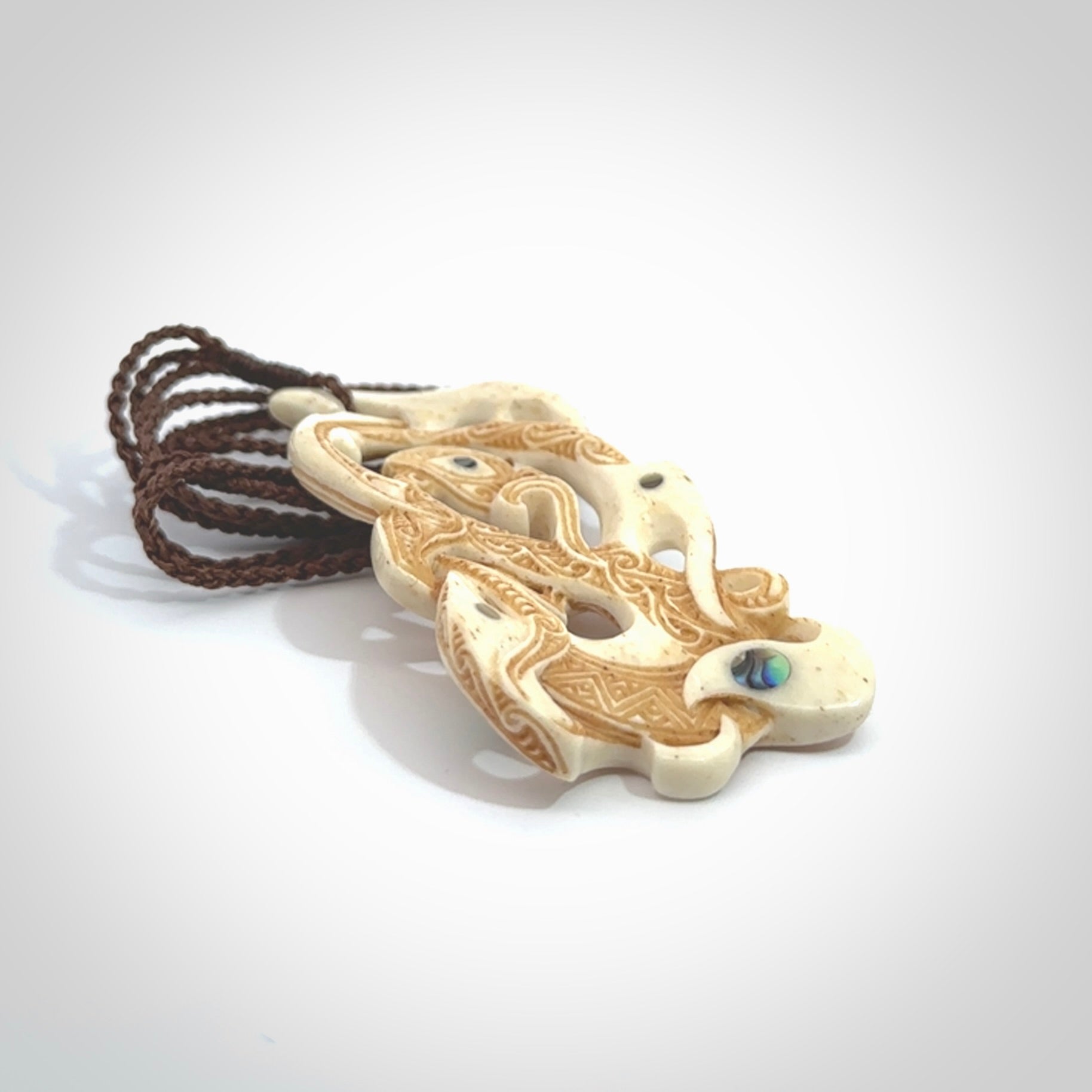 This is a wonderful, finely carved Manaia with Tiki drop pendant. It is hand carved by Andrew Doughty and we will ship it to you free anywhere in the world. Hand made from bone and delivered to you with an adjustable brown cord.