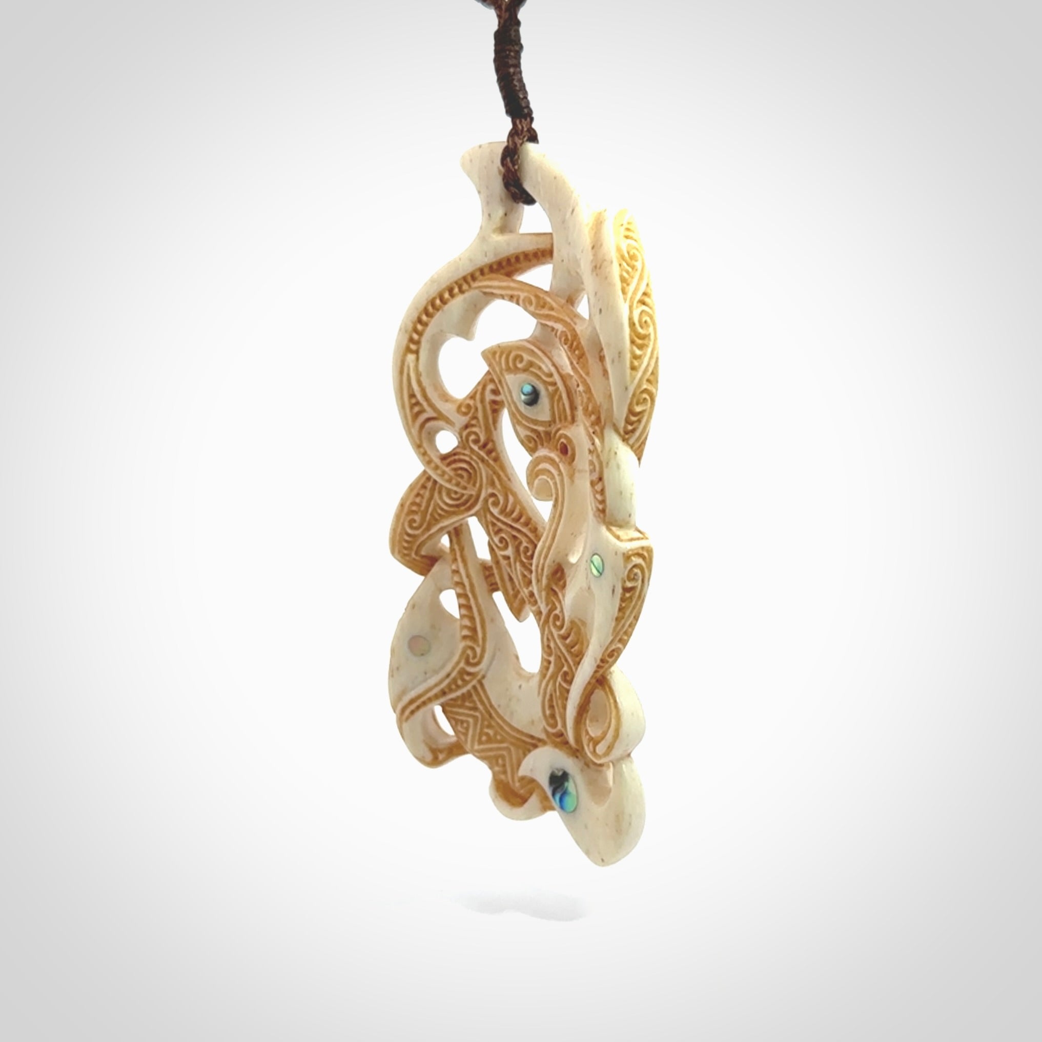 This is a wonderful, finely carved Manaia with Tiki drop pendant. It is hand carved by Andrew Doughty and we will ship it to you free anywhere in the world. Hand made from bone and delivered to you with an adjustable brown cord.