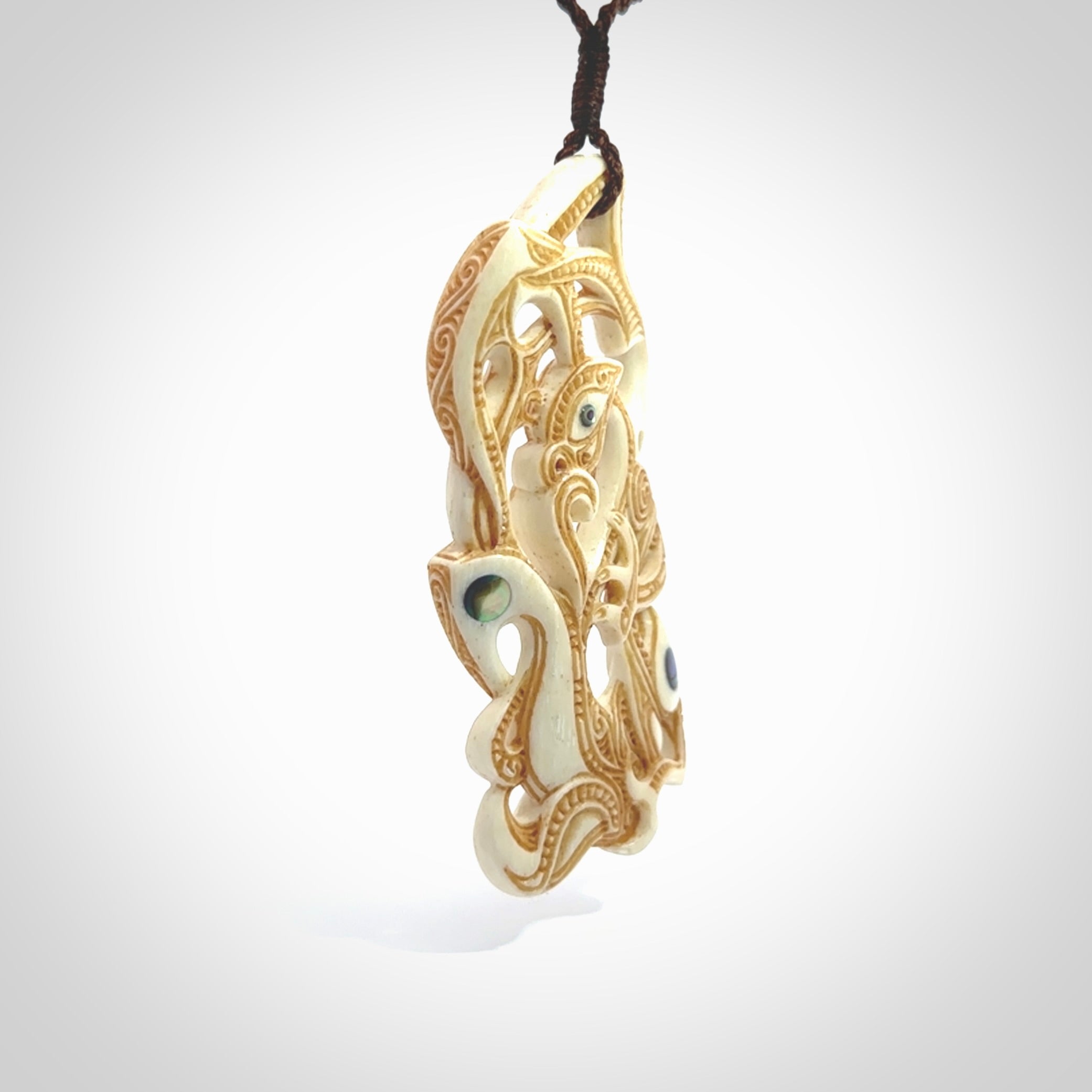 This is a wonderful, finely carved Manaia with Tiki drop pendant. It is hand carved by Andrew Doughty and we will ship it to you free anywhere in the world. Hand made from bone and delivered to you with an adjustable brown cord.