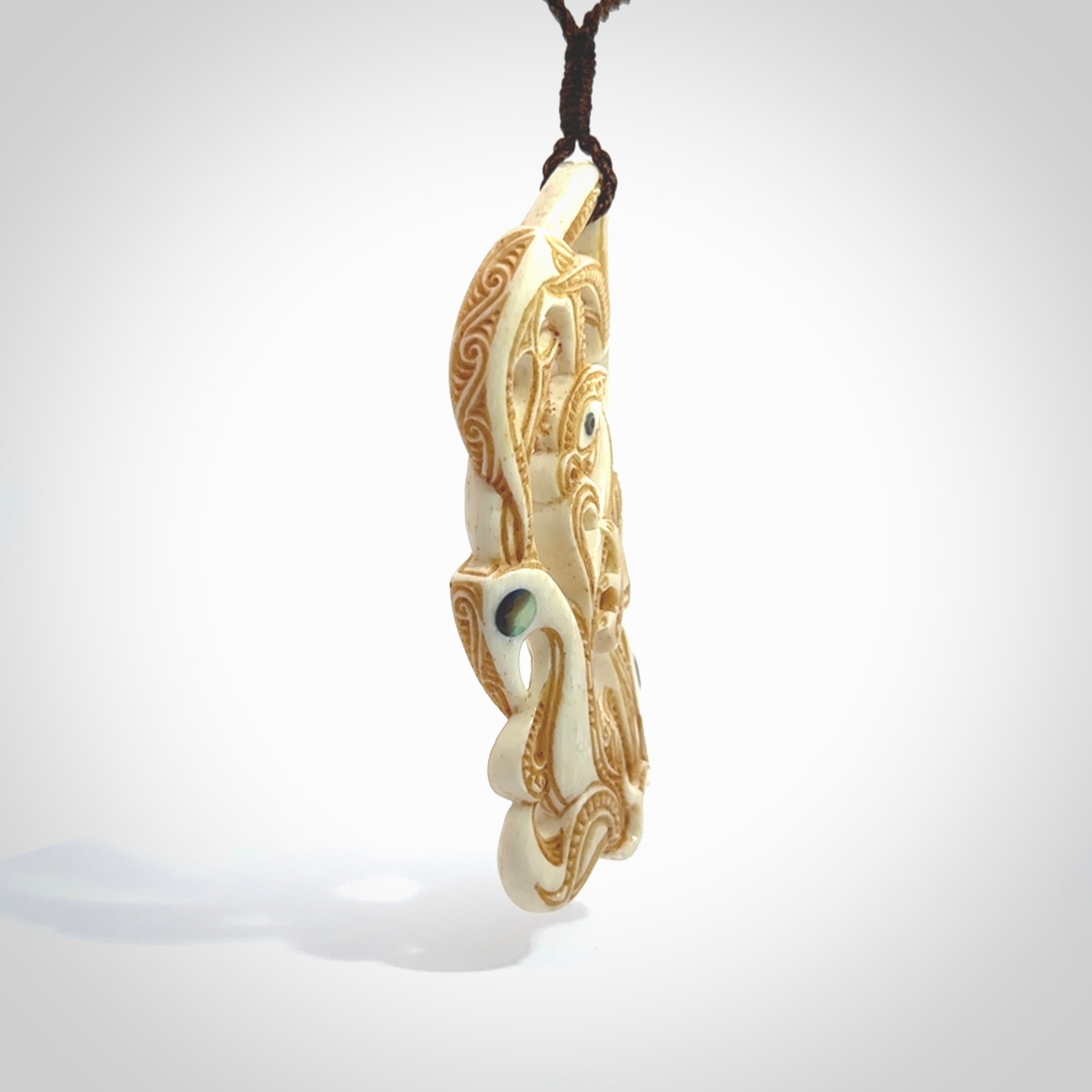 This is a wonderful, finely carved Manaia with Tiki drop pendant. It is hand carved by Andrew Doughty and we will ship it to you free anywhere in the world. Hand made from bone and delivered to you with an adjustable brown cord.