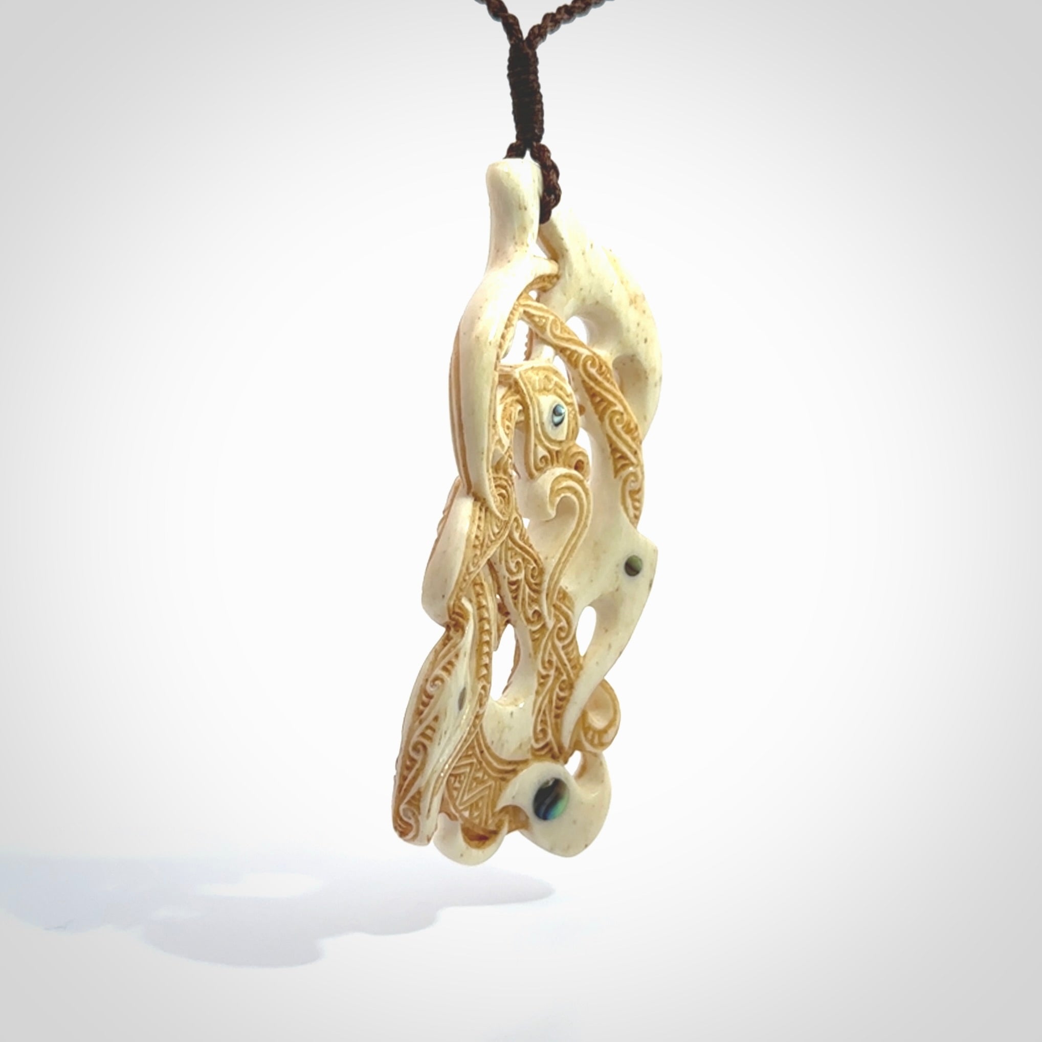 This is a wonderful, finely carved Manaia with Tiki drop pendant. It is hand carved by Andrew Doughty and we will ship it to you free anywhere in the world. Hand made from bone and delivered to you with an adjustable brown cord.