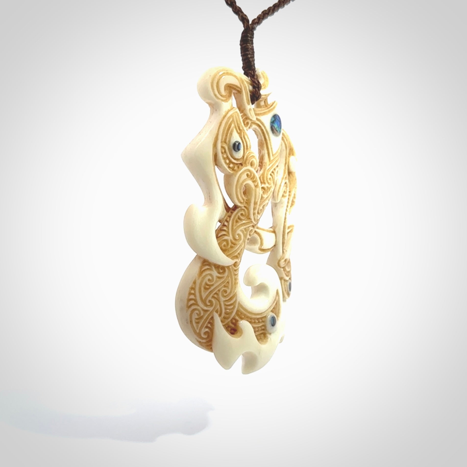 This is a wonderful, finely carved Manaia with Tiki drop pendant. It is hand carved by Andrew Doughty and we will ship it to you free anywhere in the world. Hand made from bone and delivered to you with an adjustable brown cord.