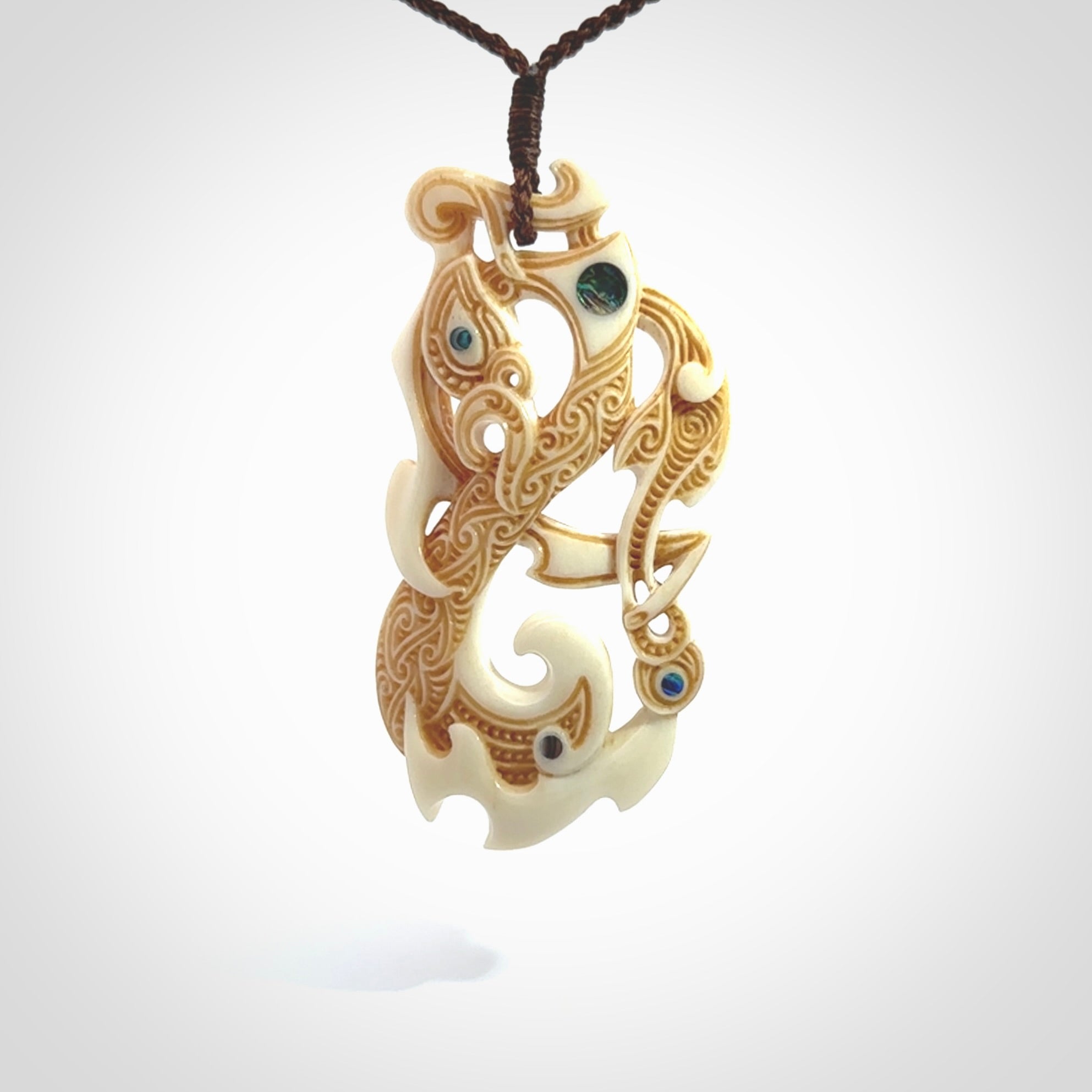 This is a wonderful, finely carved Manaia with Tiki drop pendant. It is hand carved by Andrew Doughty and we will ship it to you free anywhere in the world. Hand made from bone and delivered to you with an adjustable brown cord.