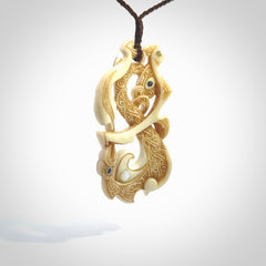 This is a wonderful, finely carved Manaia with Tiki drop pendant. It is hand carved by Andrew Doughty and we will ship it to you free anywhere in the world. Hand made from bone and delivered to you with an adjustable brown cord.