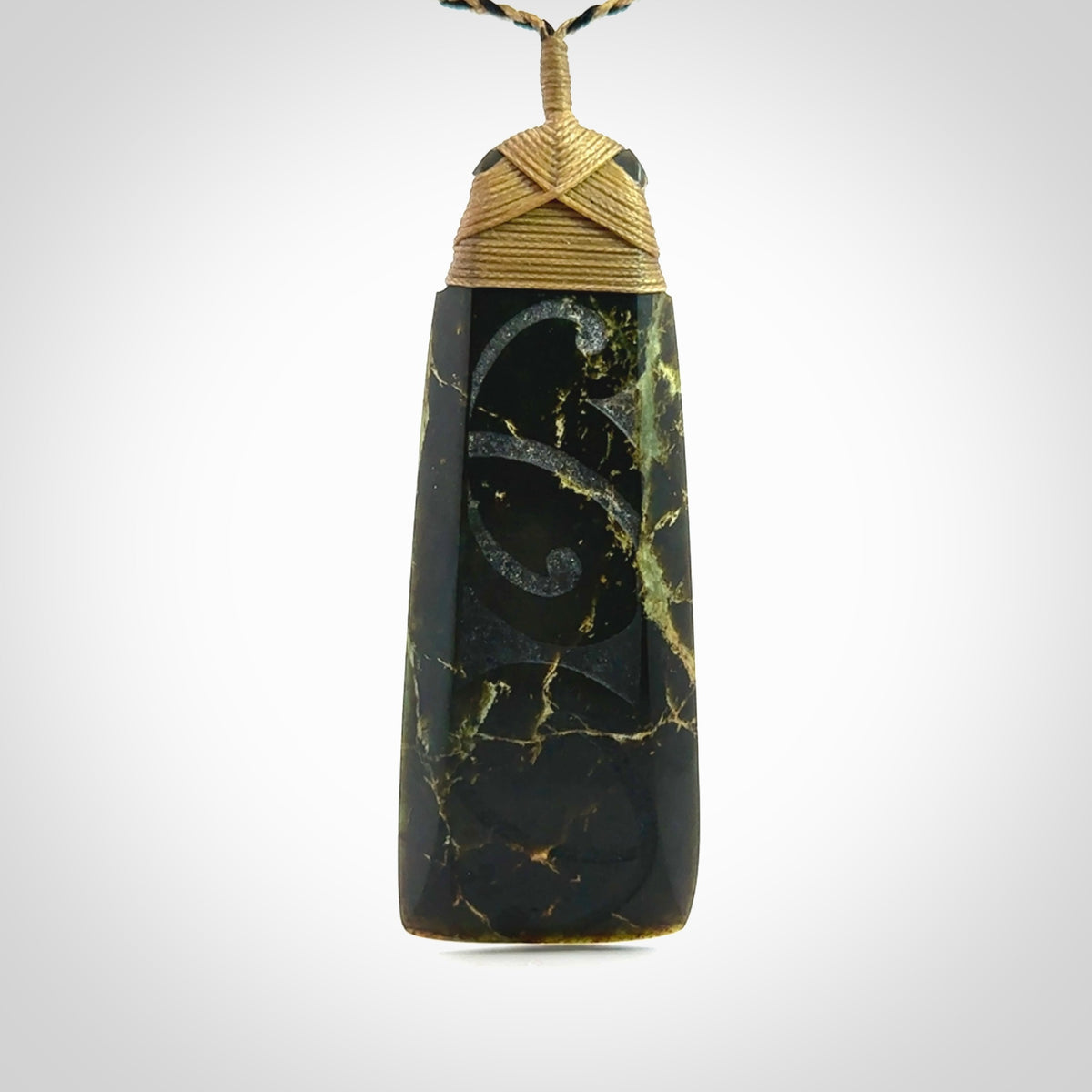 Large Jade Toki pendant. Hand carved from a lovely piece of local New Zealand Jade. The quality of the workmanship and design is outstanding - this is a piece you will want to wear all the time. We have suspended this from an adjustable 3-plait tan/black cord and tan binding.