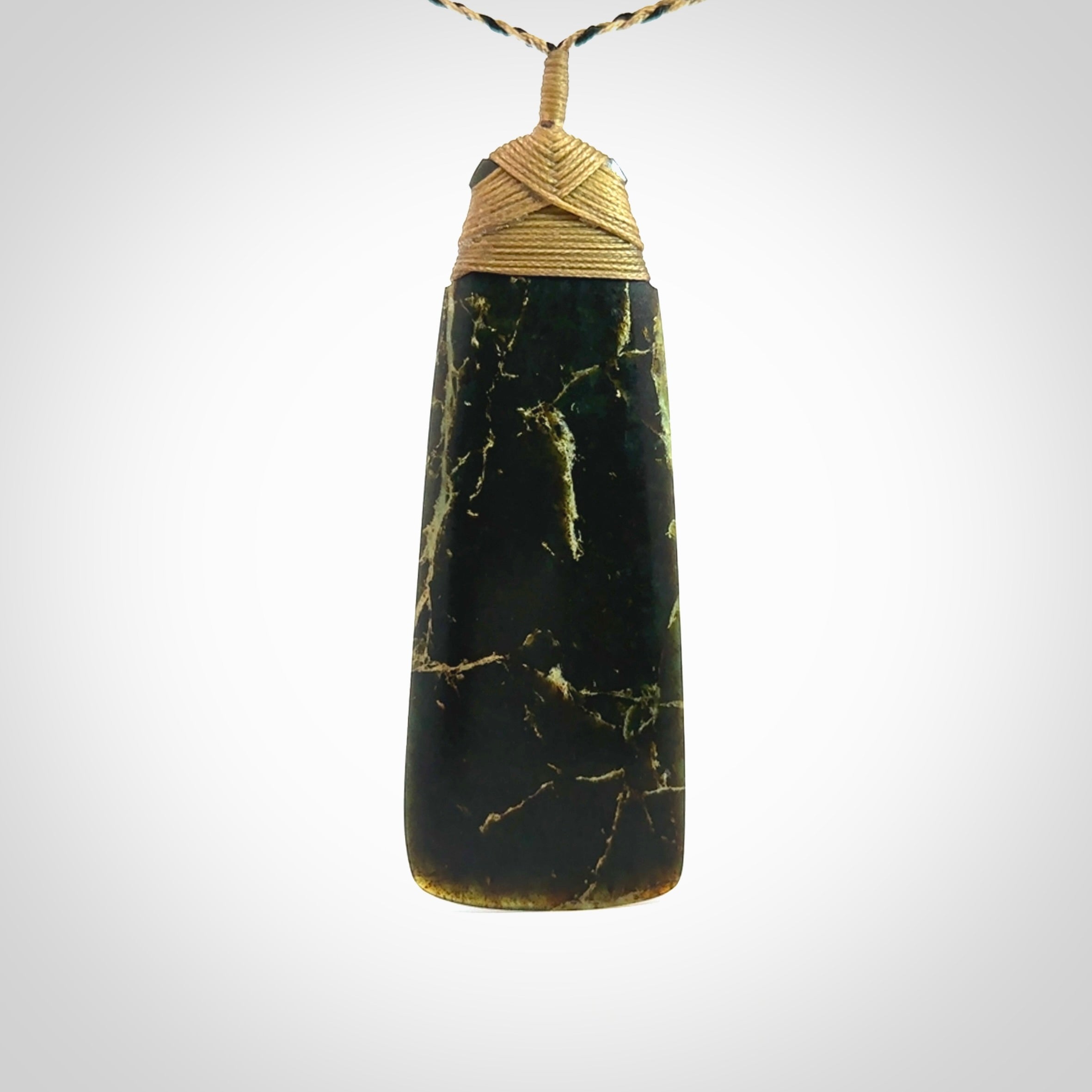 Large Jade Toki pendant. Hand carved from a lovely piece of local New Zealand Jade. The quality of the workmanship and design is outstanding - this is a piece you will want to wear all the time. We have suspended this from an adjustable 3-plait tan/black cord and tan binding.