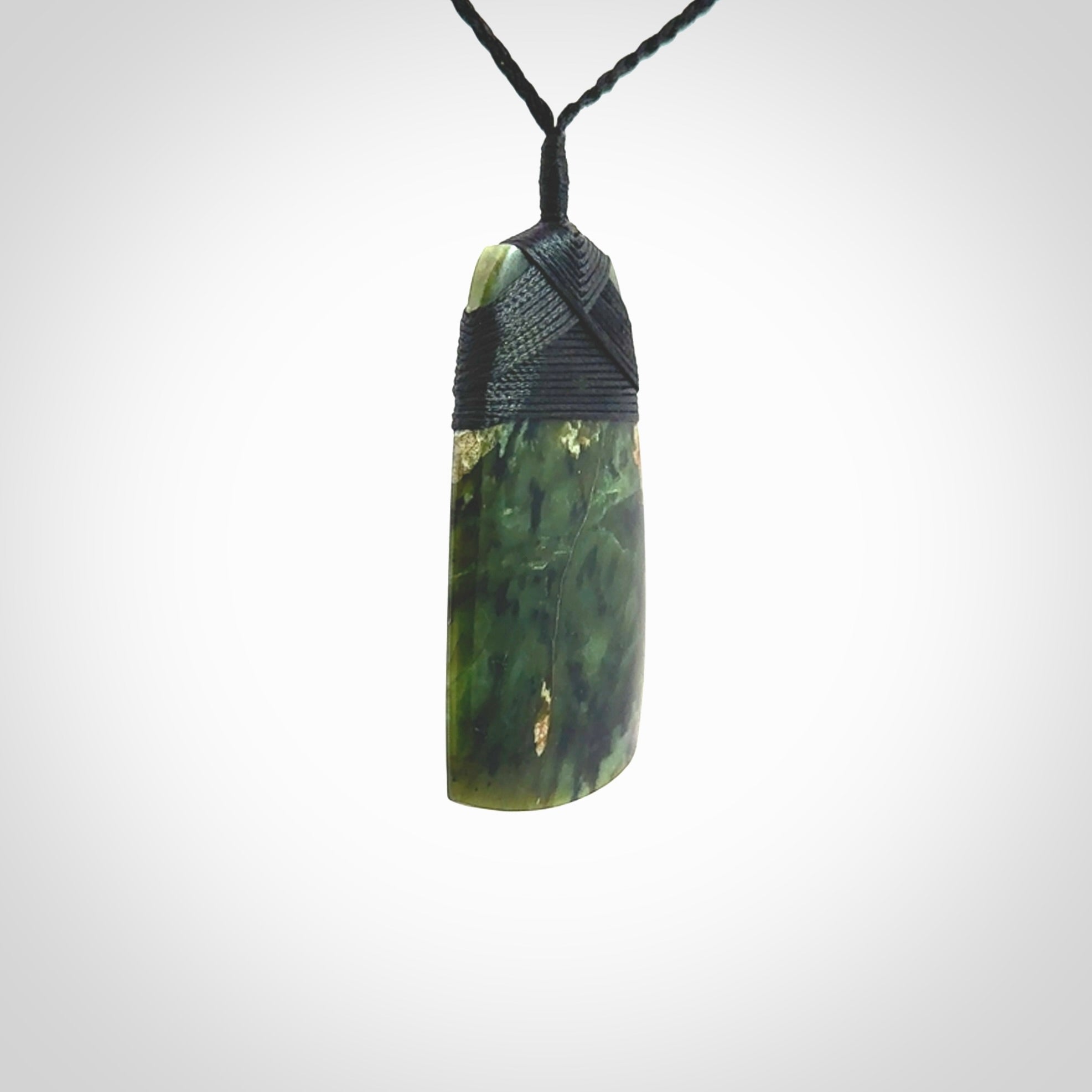 Hand carved from a lovely piece of local New Zealand Tangiwai Pounamu. The quality of the workmanship and design is outstanding - this is a piece you will want to wear all the time. We have suspended this Toki from an adjustable 3-plait black cord and binding.