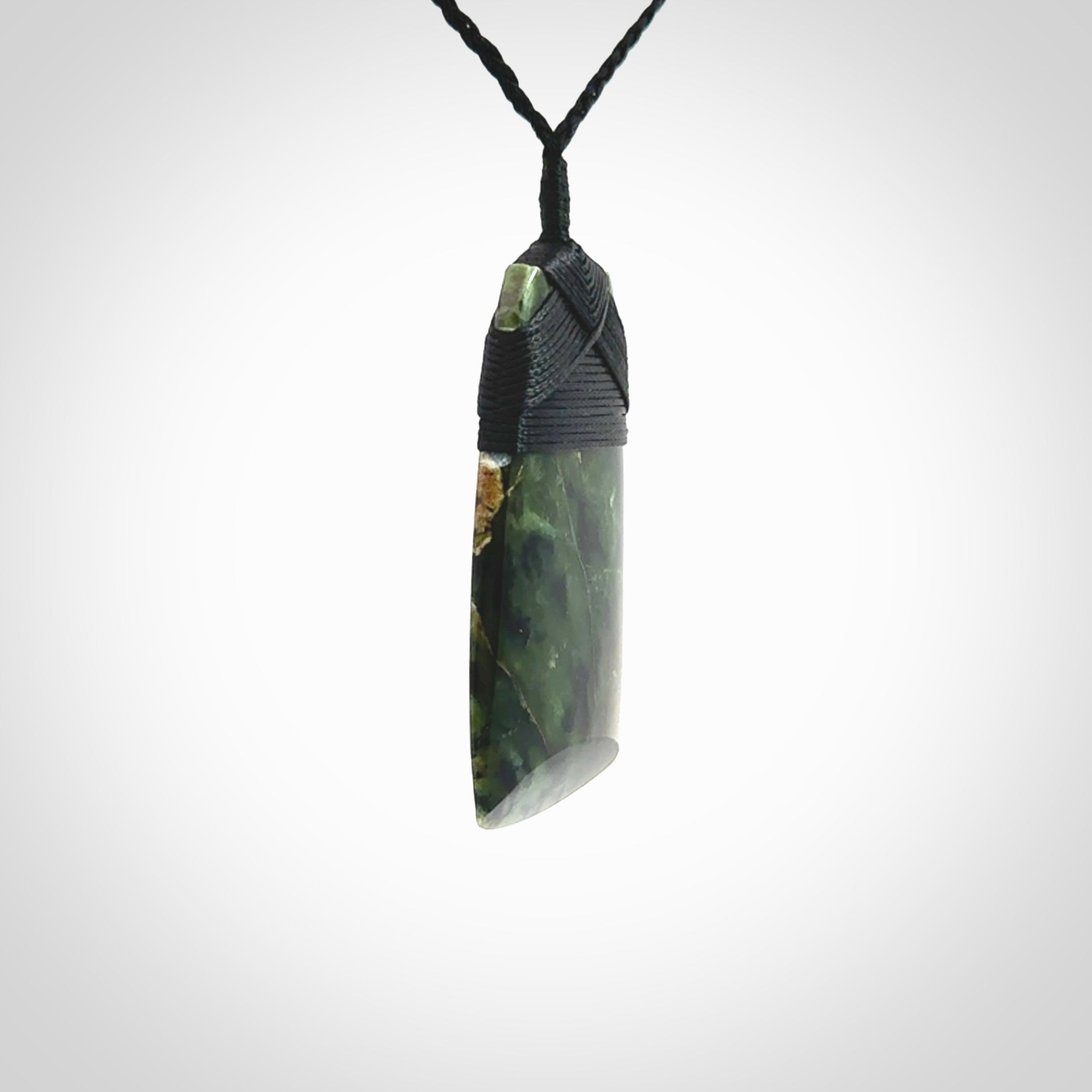 Hand carved from a lovely piece of local New Zealand Tangiwai Pounamu. The quality of the workmanship and design is outstanding - this is a piece you will want to wear all the time. We have suspended this Toki from an adjustable 3-plait black cord and binding.