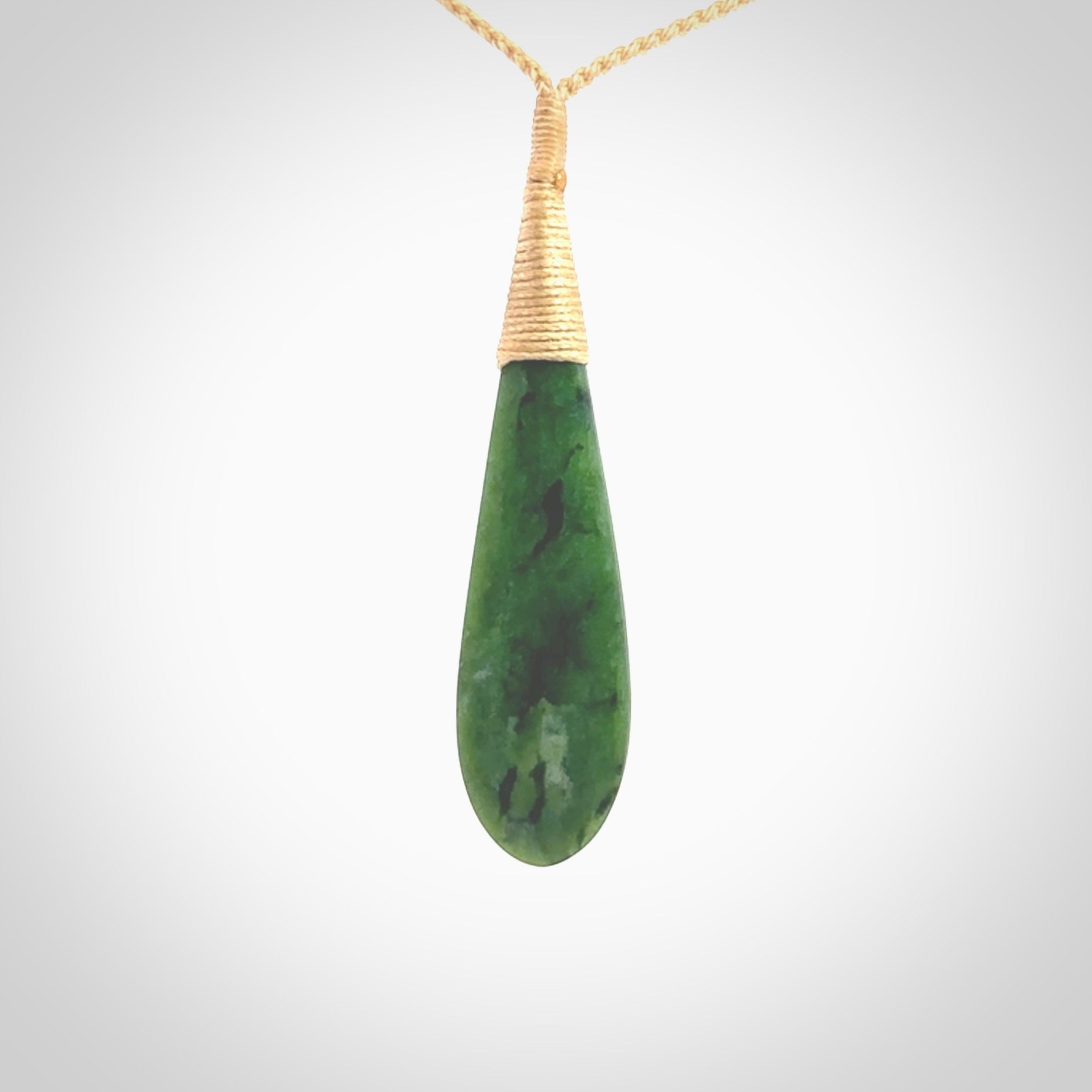 This photo shows a beautiful jade drop with paua shell inlay. It is hand carved from a piece of green New Zealand pounamu, with fascinating light green inclusions throughout the stone. We have this on a beige coloured, adjustable four plait cord. We ship this worldwide with an express courier service. Postage is free.