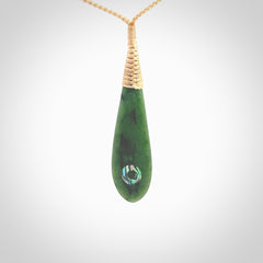 This photo shows a beautiful jade drop with paua shell inlay. It is hand carved from a piece of green New Zealand pounamu, with fascinating light green inclusions throughout the stone. We have this on a beige coloured, adjustable four plait cord. We ship this worldwide with an express courier service. Postage is free.