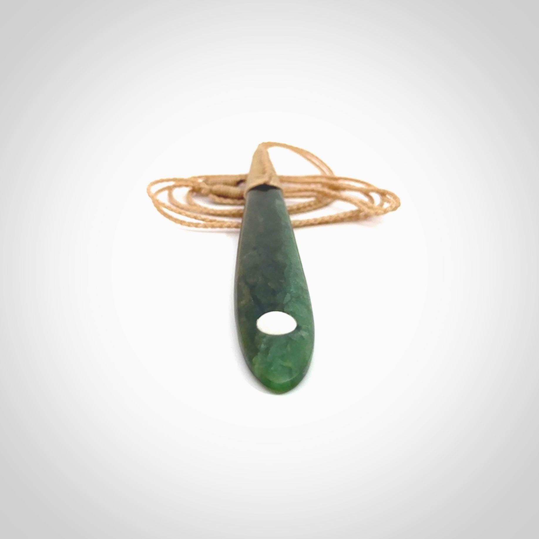 This photo shows a large beautiful jade drop with whale tooth inlay. It is hand carved from a piece of green New Zealand pounamu, with fascinating light green inclusions throughout the stone. We have this on a beige coloured, adjustable four plait cord. We ship this worldwide with an express courier service. Postage is free.