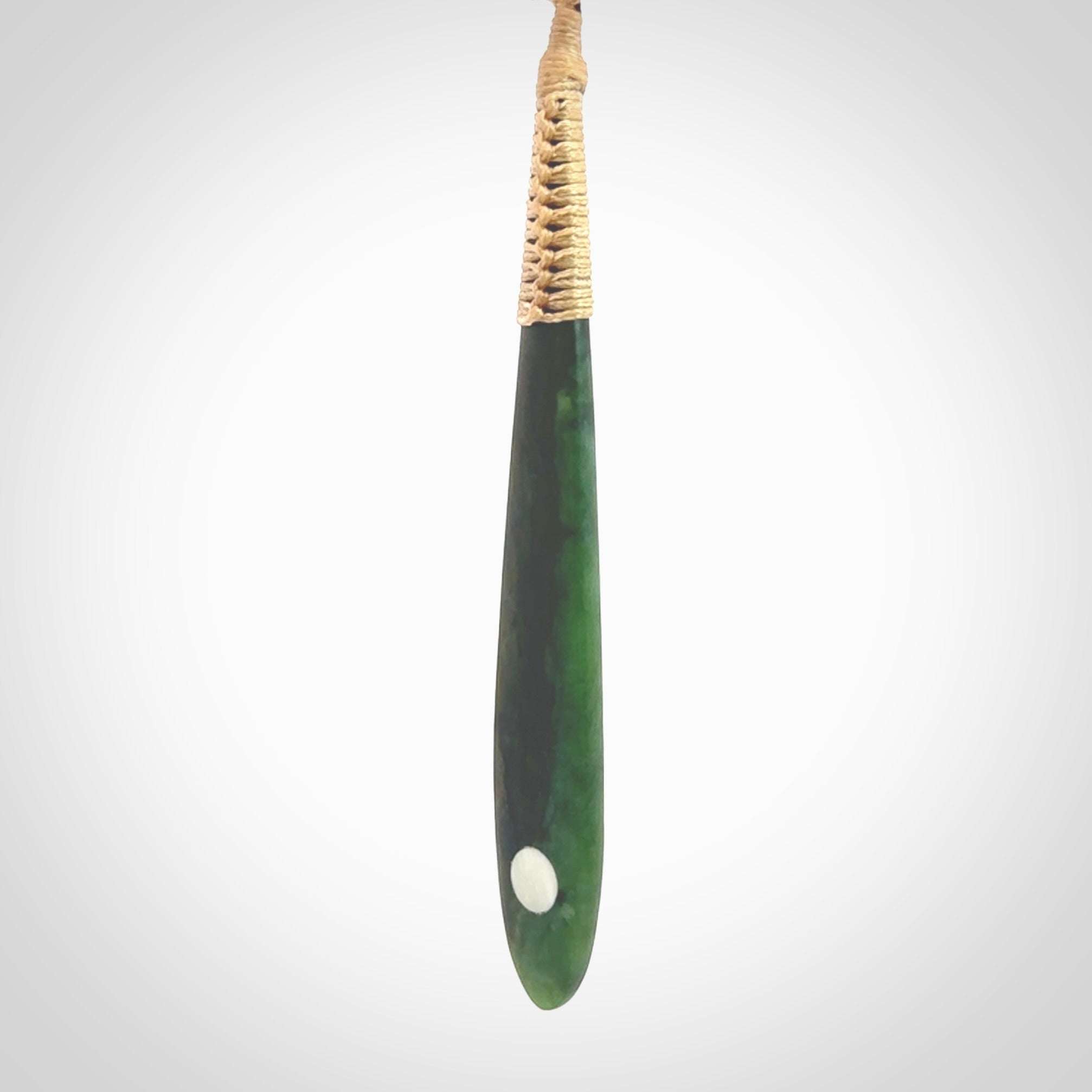 This photo shows a large beautiful jade drop with whale tooth inlay. It is hand carved from a piece of green New Zealand pounamu, with fascinating light green inclusions throughout the stone. We have this on a beige coloured, adjustable four plait cord. We ship this worldwide with an express courier service. Postage is free.