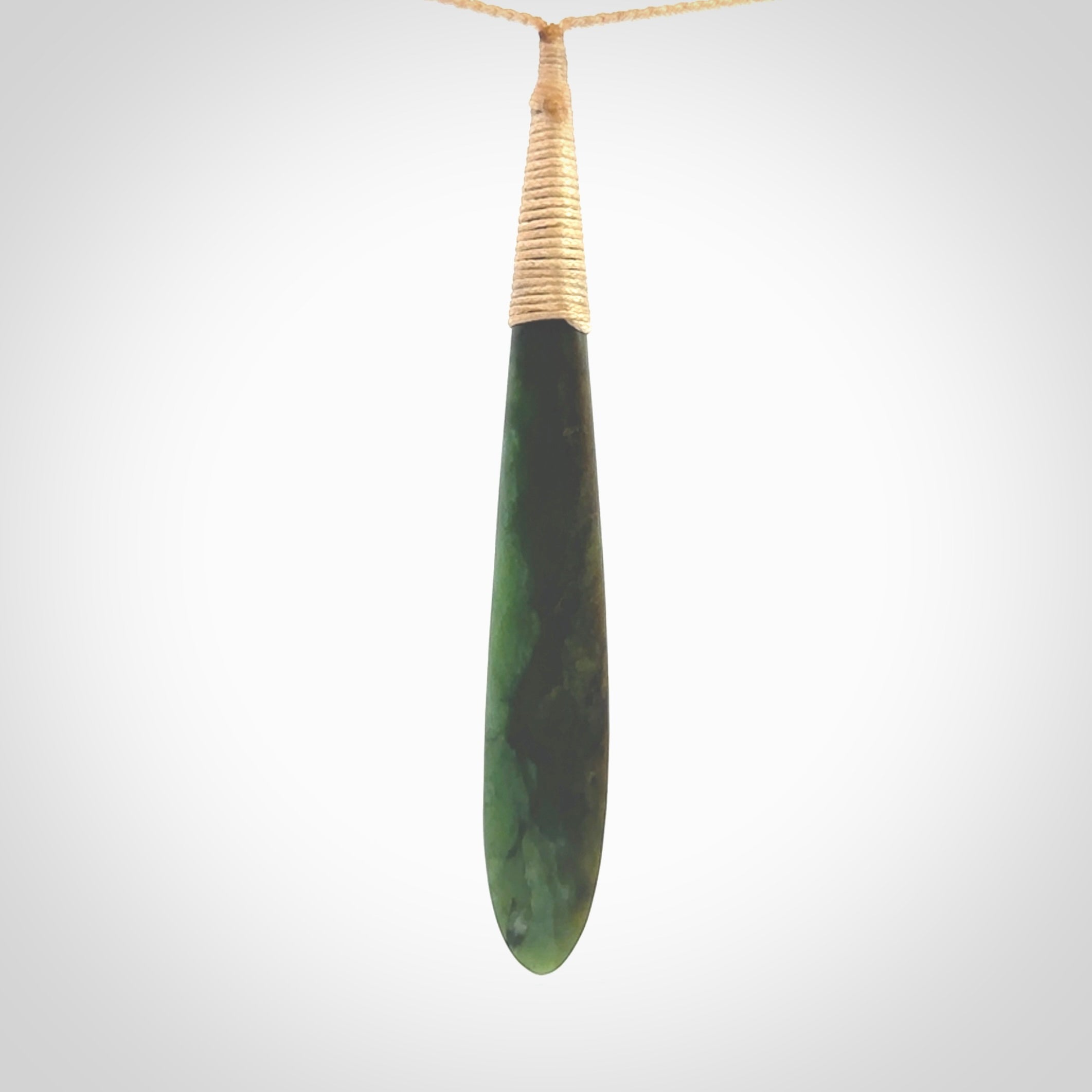 This photo shows a large beautiful jade drop with whale tooth inlay. It is hand carved from a piece of green New Zealand pounamu, with fascinating light green inclusions throughout the stone. We have this on a beige coloured, adjustable four plait cord. We ship this worldwide with an express courier service. Postage is free.