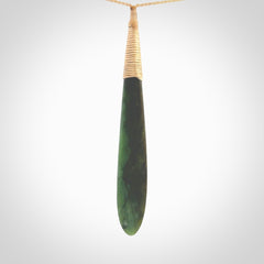 This photo shows a large beautiful jade drop with whale tooth inlay. It is hand carved from a piece of green New Zealand pounamu, with fascinating light green inclusions throughout the stone. We have this on a beige coloured, adjustable four plait cord. We ship this worldwide with an express courier service. Postage is free.