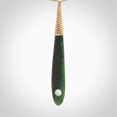 This photo shows a large beautiful jade drop with whale tooth inlay. It is hand carved from a piece of green New Zealand pounamu, with fascinating light green inclusions throughout the stone. We have this on a beige coloured, adjustable four plait cord. We ship this worldwide with an express courier service. Postage is free.