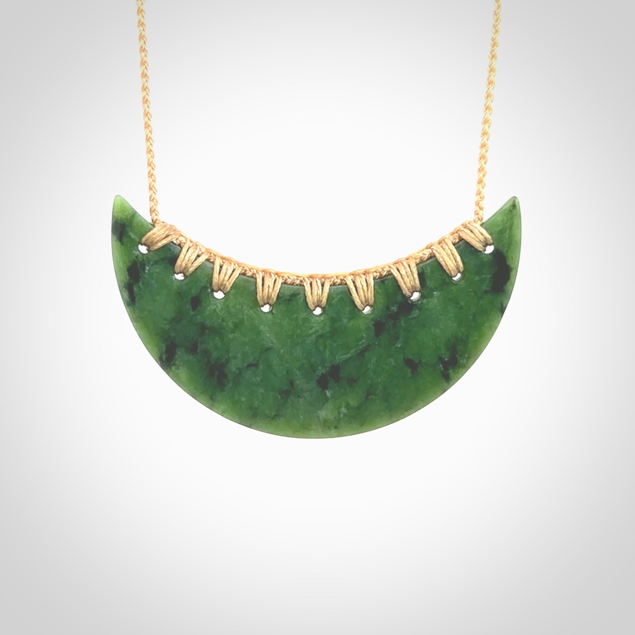 This picture shows a large hand carved jade contemporary half-shield pendant with Paua Shell inlay. It is a deep green and is a wonderful, delicate piece of jewellery. The cord is hand plaited and adjustable so that you can position the pendant where it suits you best. This piece was carved for us by Kyohei Noguchi. Delivery is free worldwide.