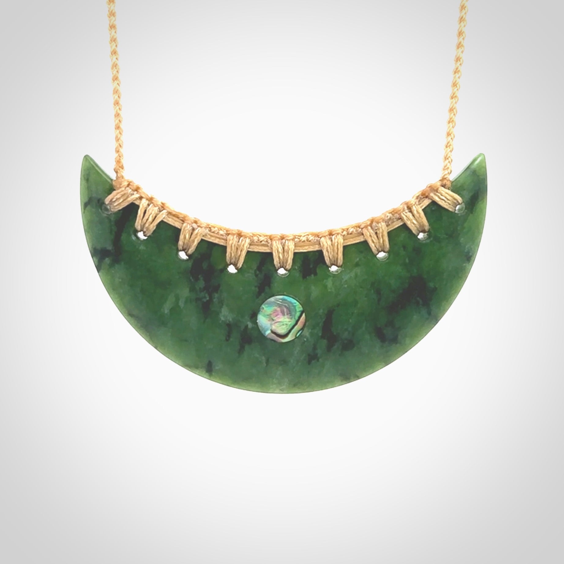 This picture shows a large hand carved jade contemporary half-shield pendant with Paua Shell inlay. It is a deep green and is a wonderful, delicate piece of jewellery. The cord is hand plaited and adjustable so that you can position the pendant where it suits you best. This piece was carved for us by Kyohei Noguchi. Delivery is free worldwide.