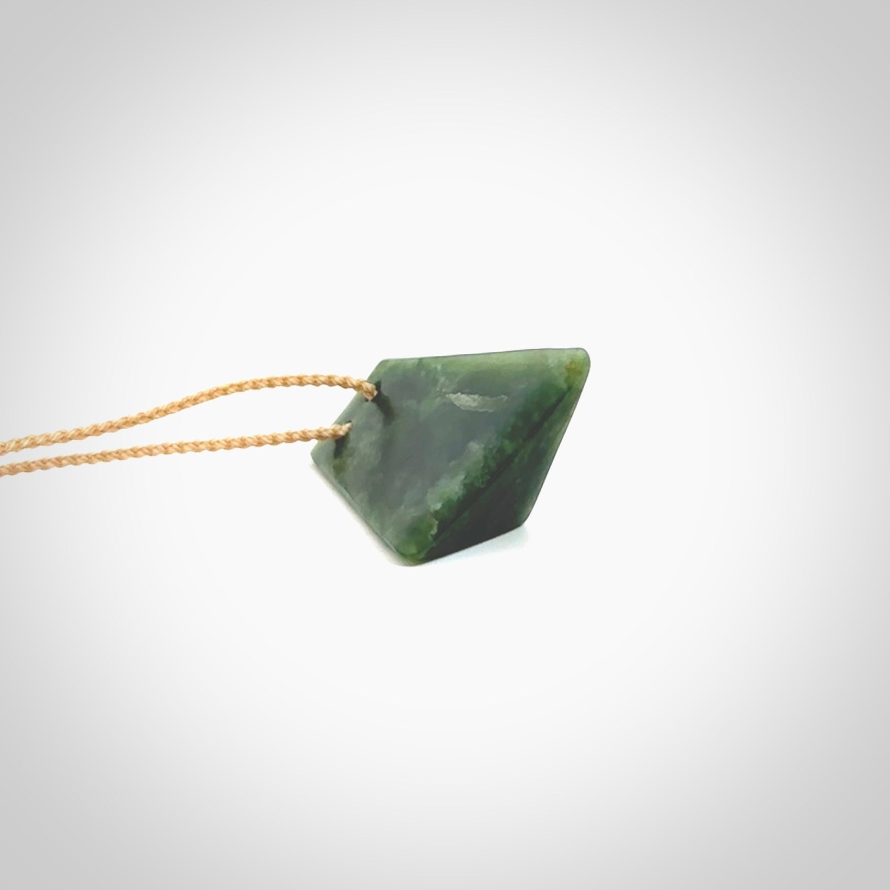 This is a lovely New Zealand Jade, pounamu drop pendant. Hand carved for us by Ric Moor. It is bound with an adjustable beige coloured cord which is length adjustable. Free worldwide shipping. The light reveals the internal structure and colour of the stone beautifully.