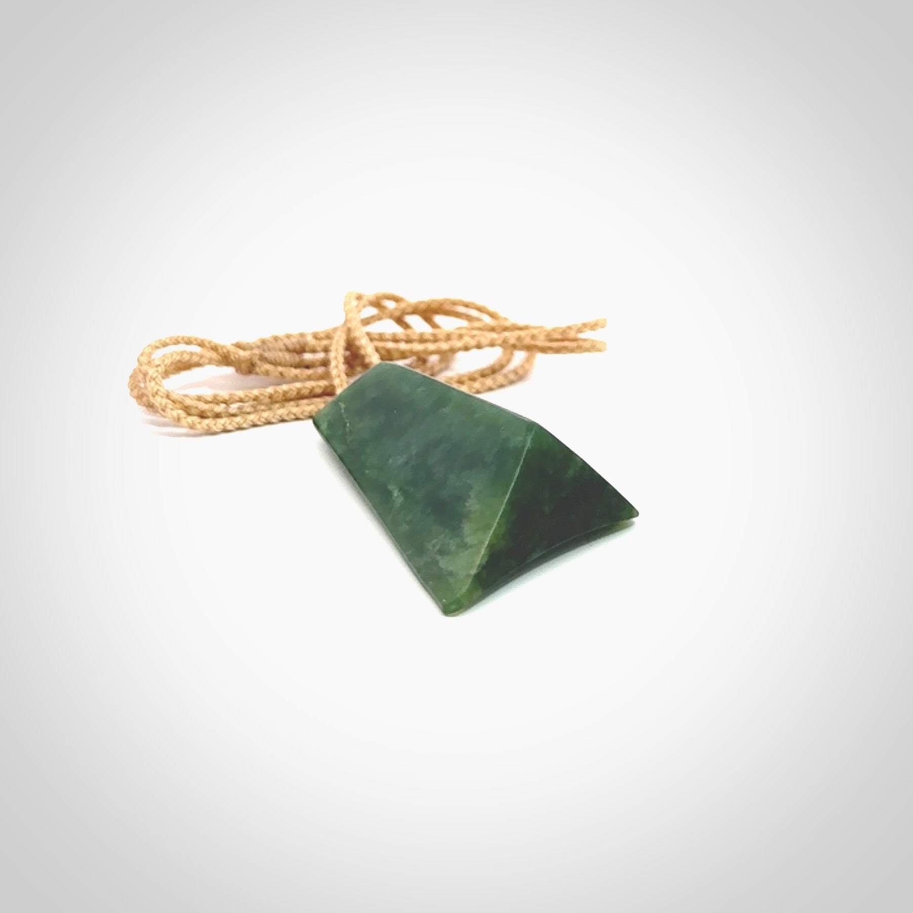 This is a lovely New Zealand Jade, pounamu drop pendant. Hand carved for us by Ric Moor. It is bound with an adjustable beige coloured cord which is length adjustable. Free worldwide shipping. The light reveals the internal structure and colour of the stone beautifully.