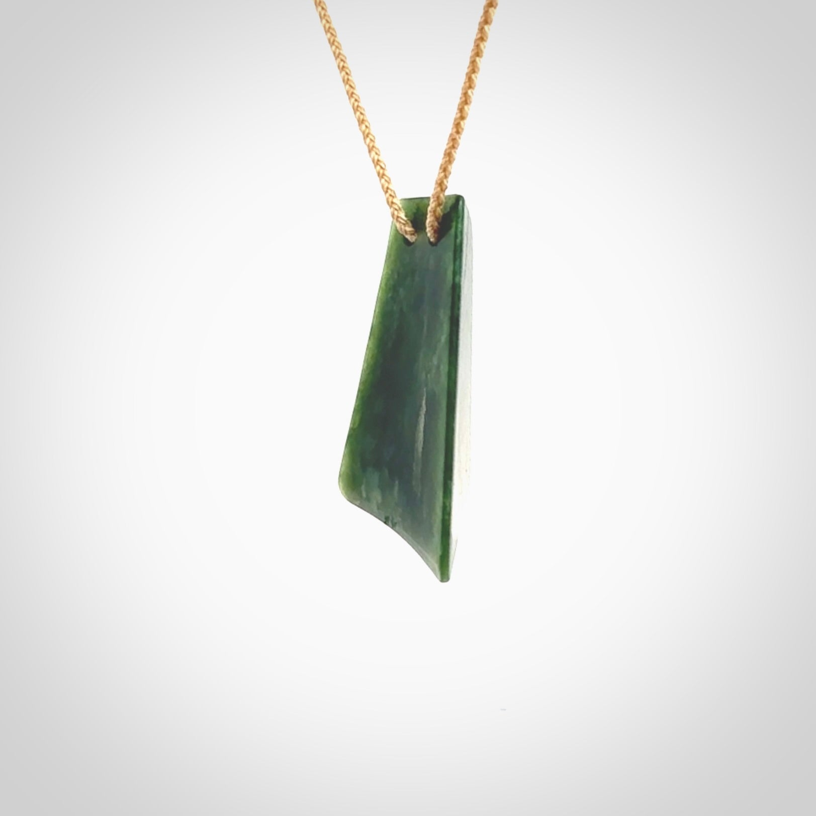 This is a lovely New Zealand Jade, pounamu drop pendant. Hand carved for us by Ric Moor. It is bound with an adjustable beige coloured cord which is length adjustable. Free worldwide shipping. The light reveals the internal structure and colour of the stone beautifully.