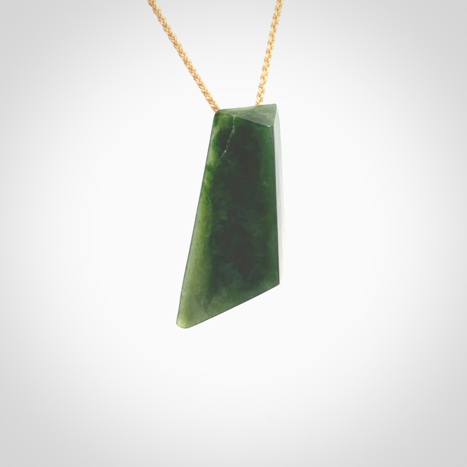 This is a lovely New Zealand Jade, pounamu drop pendant. Hand carved for us by Ric Moor. It is bound with an adjustable beige coloured cord which is length adjustable. Free worldwide shipping. The light reveals the internal structure and colour of the stone beautifully.