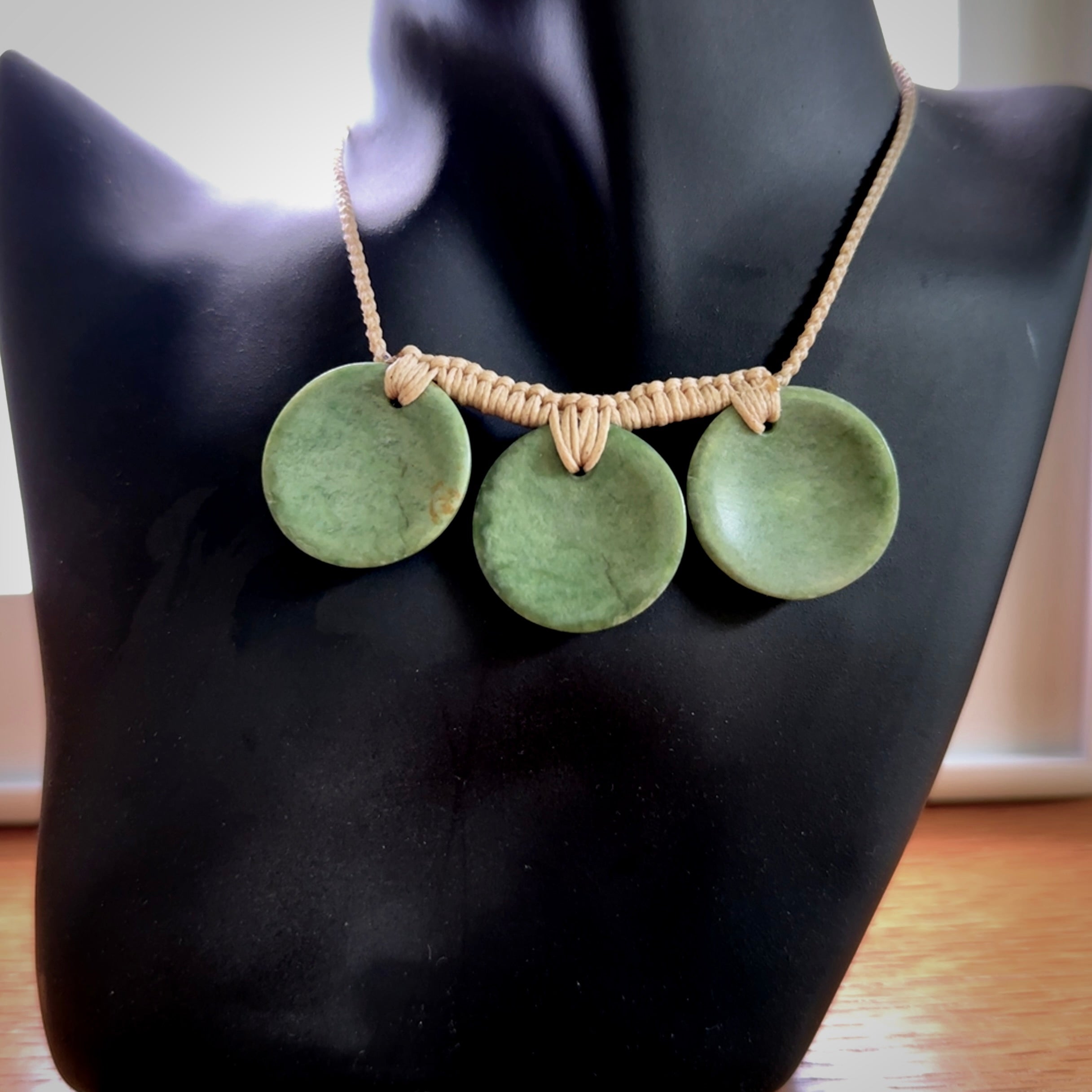 This piece is a triple disc pendant. It was carved for us by Ric Moor from a lovely light and milky green piece of New Zealand jade. It is suspended on a beige coloured braided cord that is length adjustable. One only.