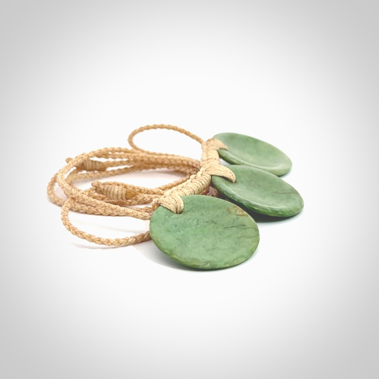 This piece is a triple disc pendant. It was carved for us by Ric Moor from a lovely light and milky green piece of New Zealand jade. It is suspended on a beige coloured braided cord that is length adjustable. One only.