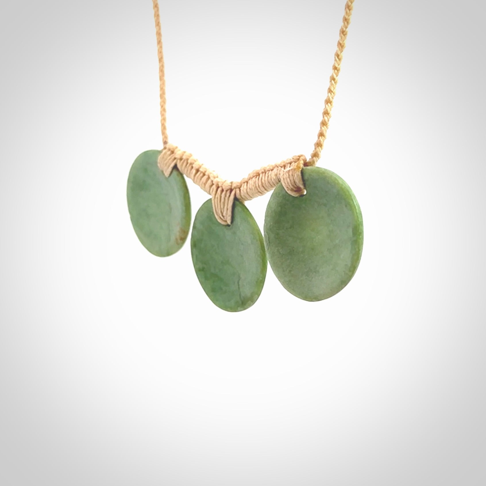 This piece is a triple disc pendant. It was carved for us by Ric Moor from a lovely light and milky green piece of New Zealand jade. It is suspended on a beige coloured braided cord that is length adjustable. One only.