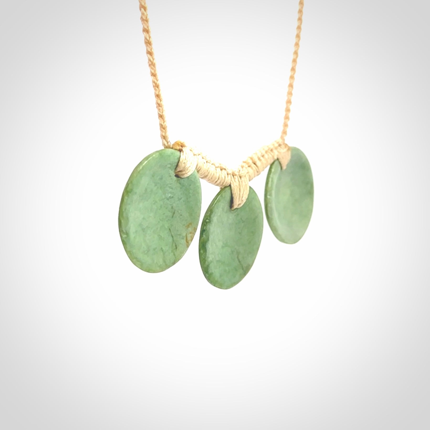 This piece is a triple disc pendant. It was carved for us by Ric Moor from a lovely light and milky green piece of New Zealand jade. It is suspended on a beige coloured braided cord that is length adjustable. One only.