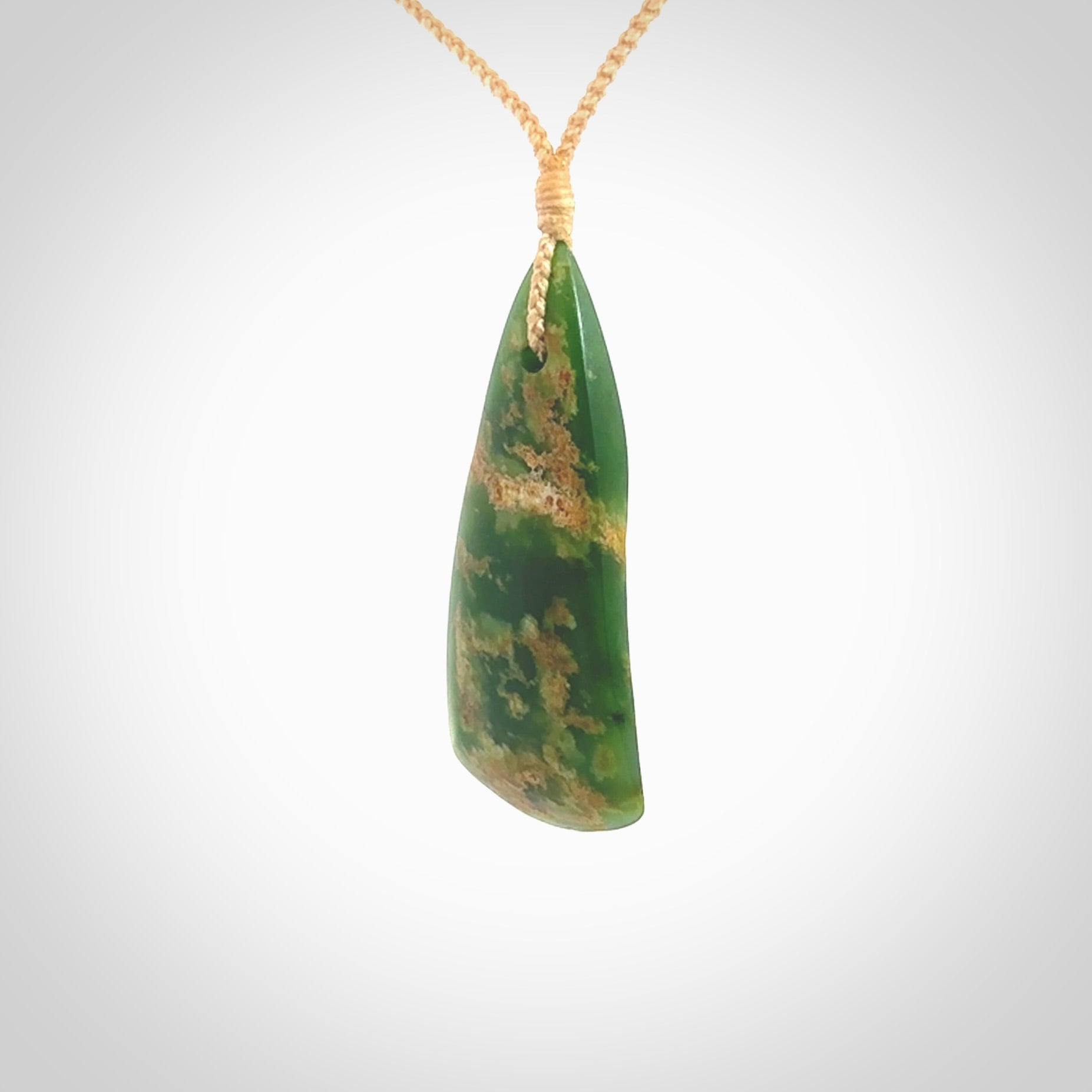 This photo shows a large jade drop shaped pendant. It a a lovely green and orange jade. The cord is a four plait beige and is adjustable in length. One only large, contemporary drop necklace from Jade, by Ric Moor.