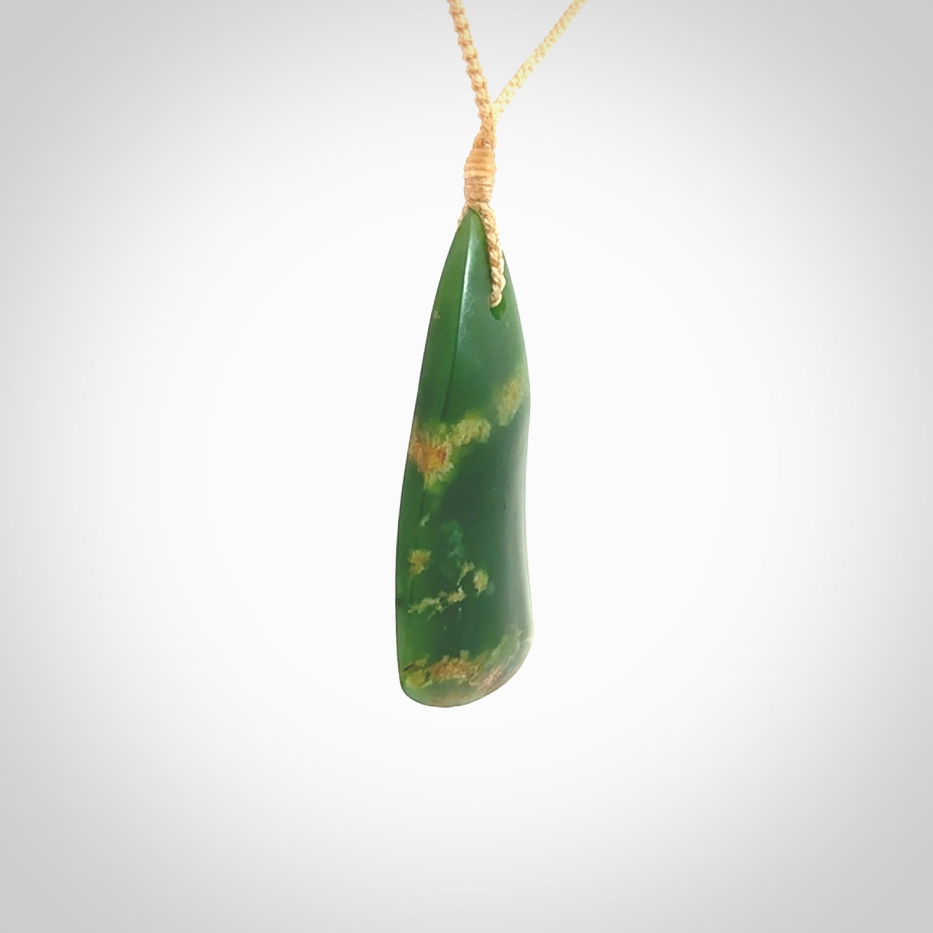 This photo shows a large jade drop shaped pendant. It a a lovely green and orange jade. The cord is a four plait beige and is adjustable in length. One only large, contemporary drop necklace from Jade, by Ric Moor.