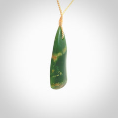 This photo shows a large jade drop shaped pendant. It a a lovely green and orange jade. The cord is a four plait beige and is adjustable in length. One only large, contemporary drop necklace from Jade, by Ric Moor.