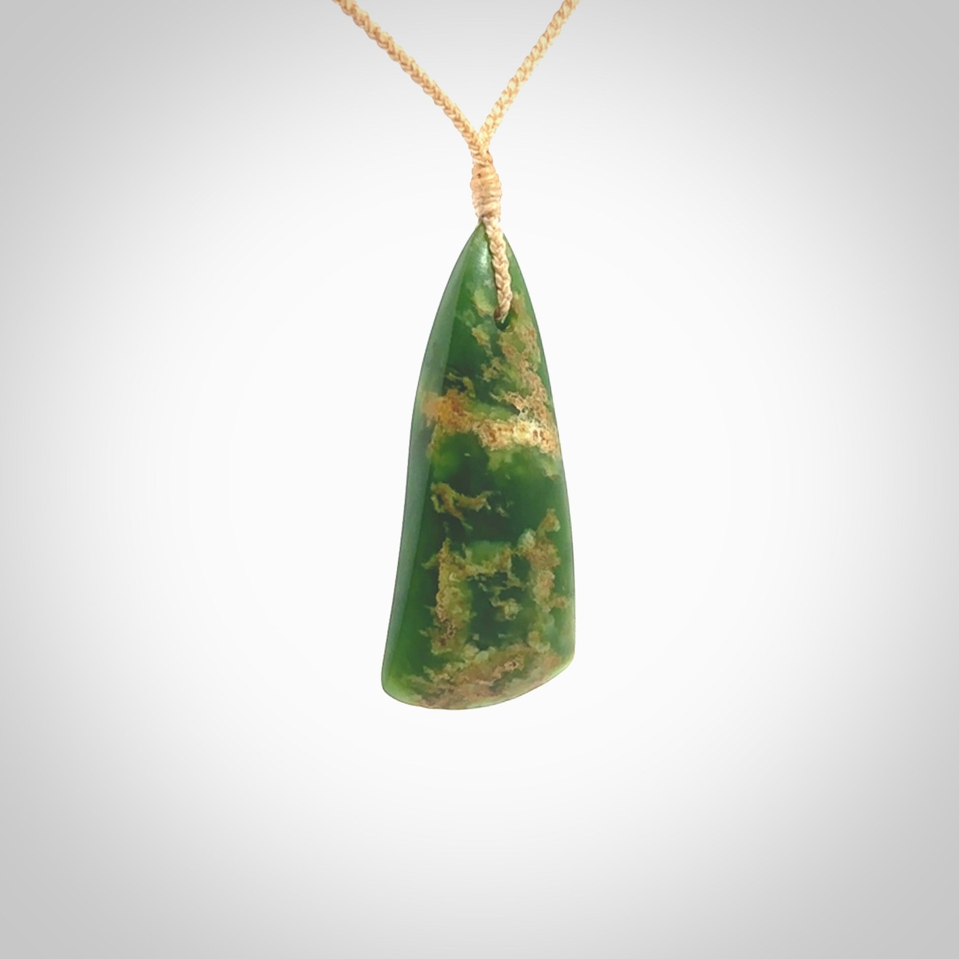 This photo shows a large jade drop shaped pendant. It a a lovely green and orange jade. The cord is a four plait beige and is adjustable in length. One only large, contemporary drop necklace from Jade, by Ric Moor.