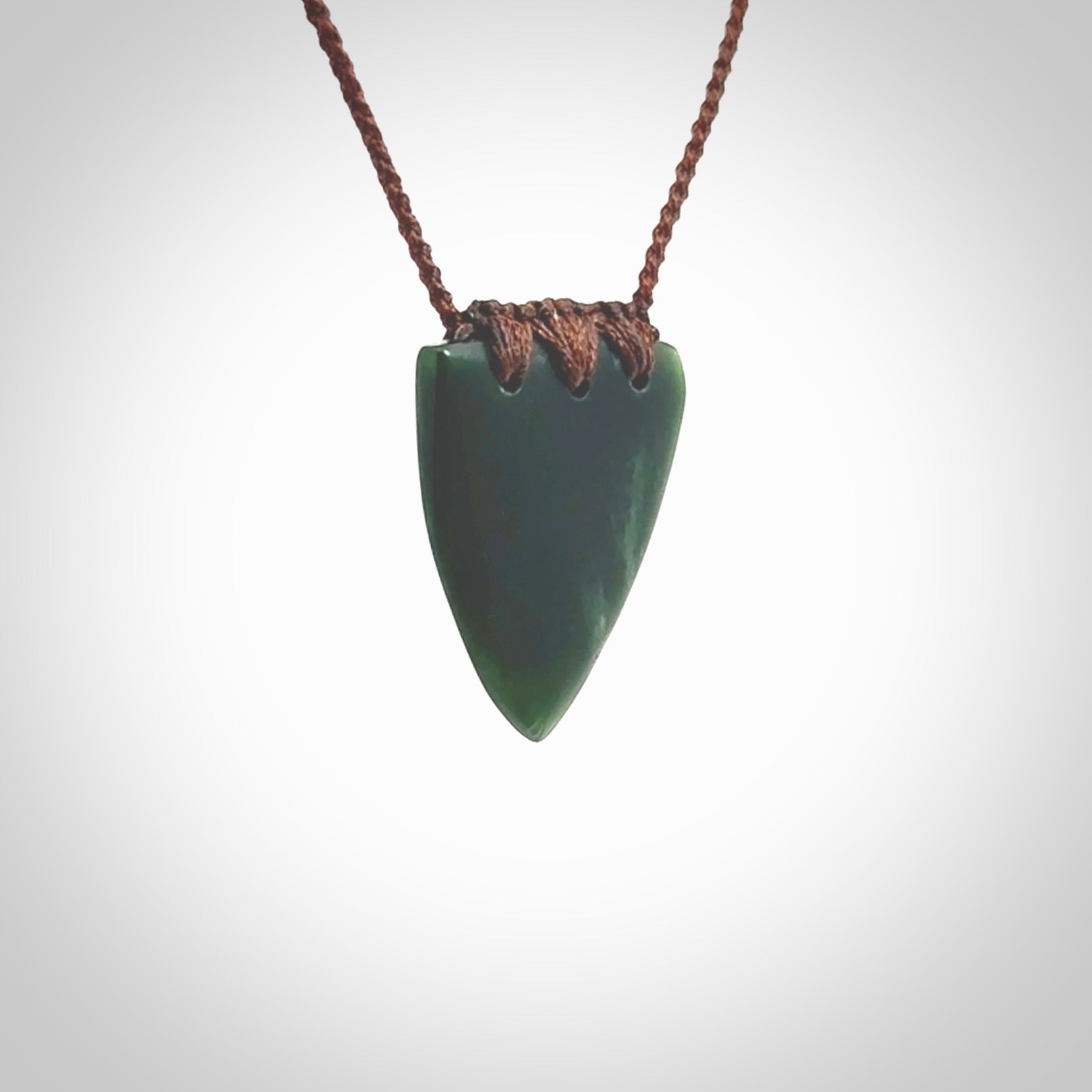 This photo shows a jade drop shaped pendant. It a a lovely deep green jade. The cord is a four plait brown and is adjustable in length. One only medium, contemporary drop necklace from Jade, by Ric Moor.