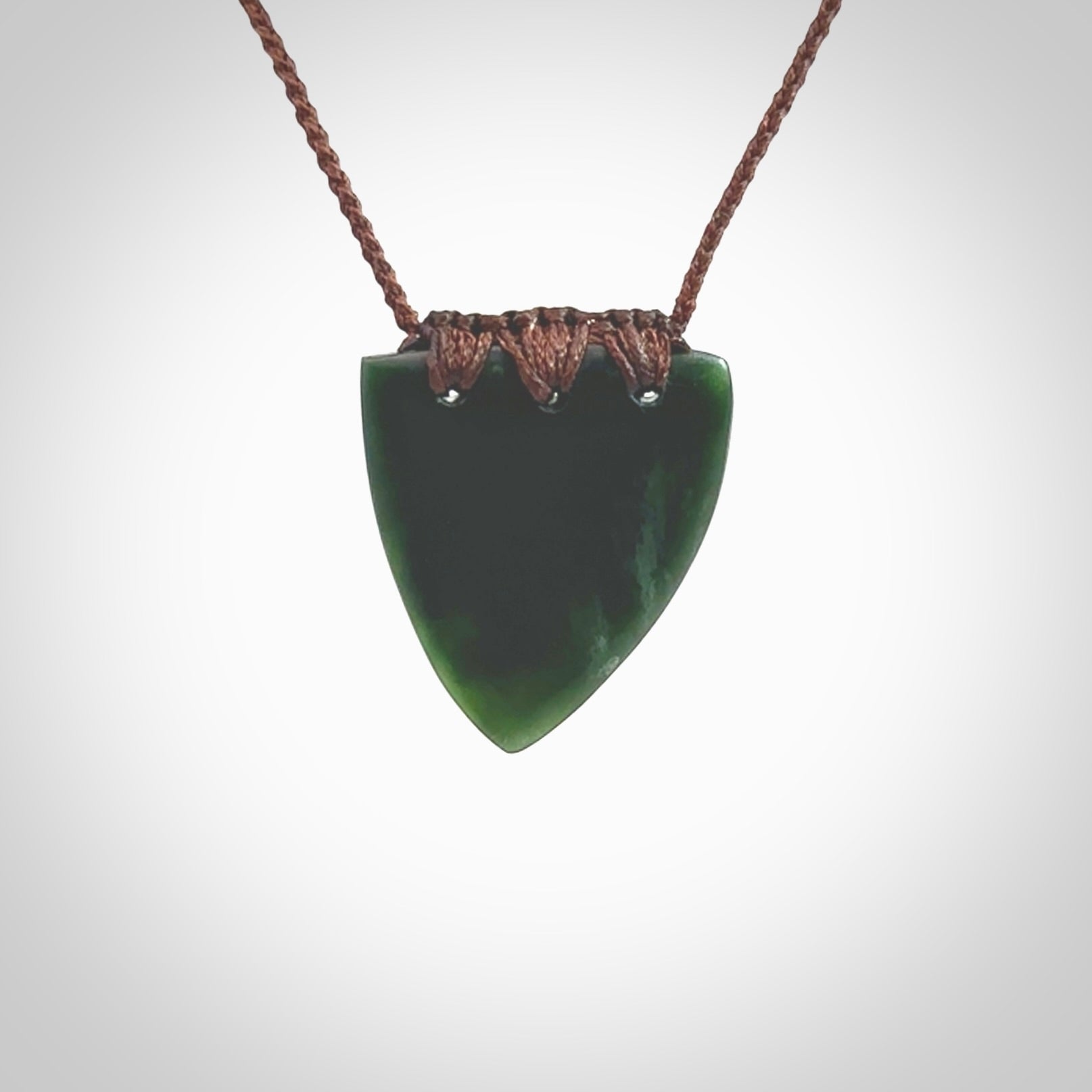 This photo shows a jade drop shaped pendant. It a a lovely deep green jade. The cord is a four plait brown and is adjustable in length. One only medium, contemporary drop necklace from Jade, by Ric Moor.