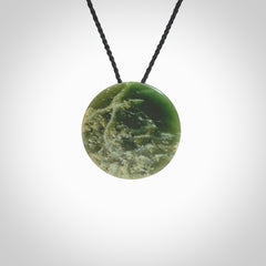 This piece is a oval round, disc pendant. It was carved for us by Ric Moor from an exquisite piece of New Zealand jade. It is suspended on a black coloured braided cord that is length adjustable.