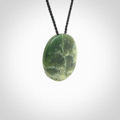 This piece is a oval round, disc pendant. It was carved for us by Ric Moor from an exquisite piece of New Zealand jade. It is suspended on a black coloured braided cord that is length adjustable.