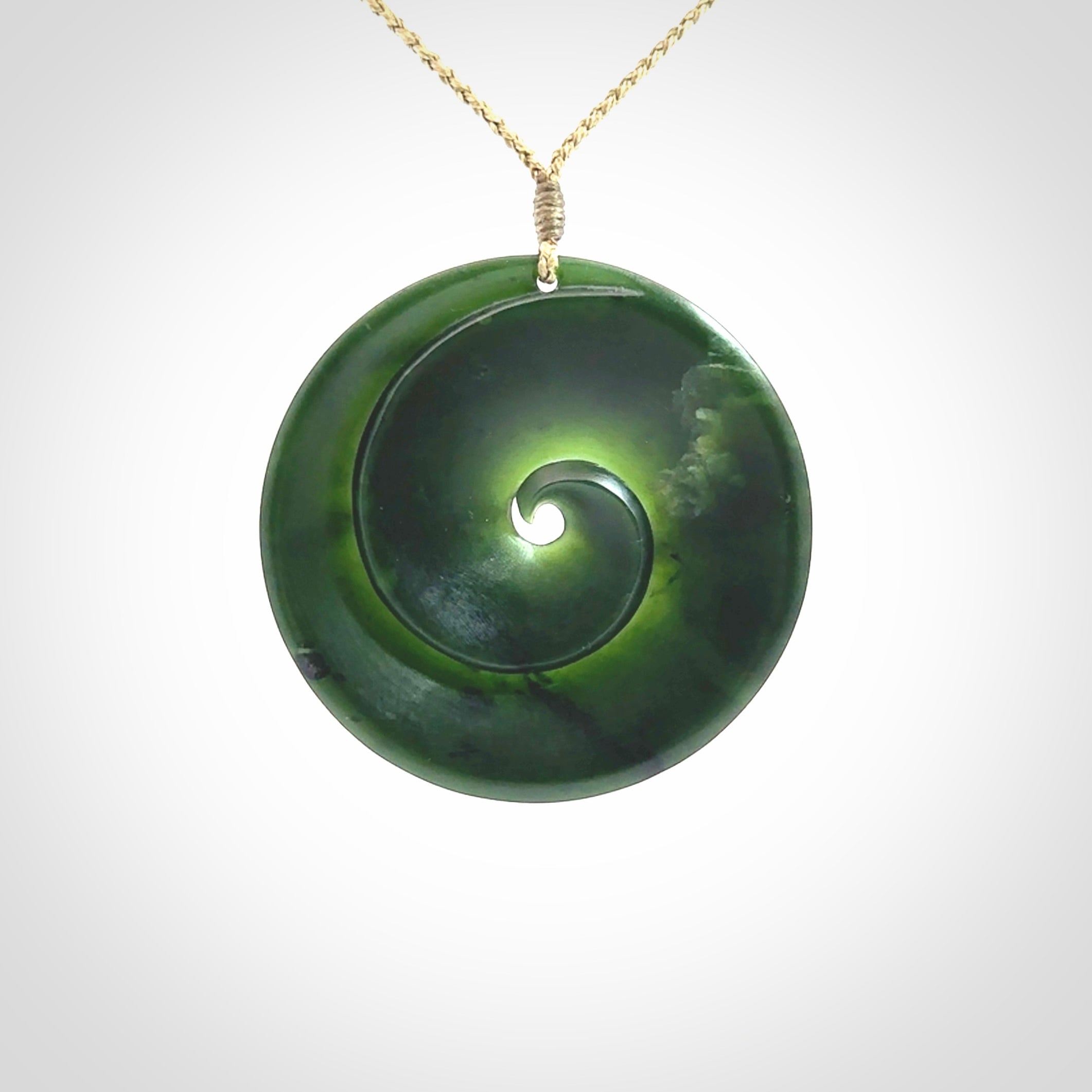 This is a large green New Zealand jade cupped koru pendant. We have bound this with a khaki coloured cord necklace. The necklace is adjustable so you can position the piece where it suits you the best. Hand made by Ric Moor.