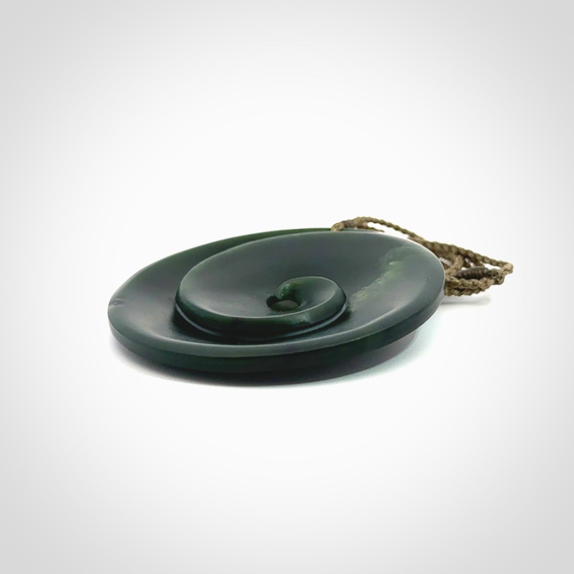 This is a large green New Zealand jade cupped koru pendant. We have bound this with a khaki coloured cord necklace. The necklace is adjustable so you can position the piece where it suits you the best. Hand made by Ric Moor.