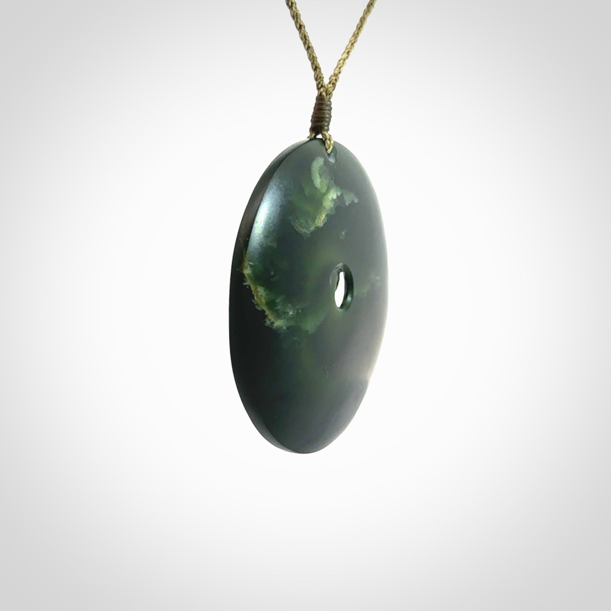 This is a large green New Zealand jade cupped koru pendant. We have bound this with a khaki coloured cord necklace. The necklace is adjustable so you can position the piece where it suits you the best. Hand made by Ric Moor.