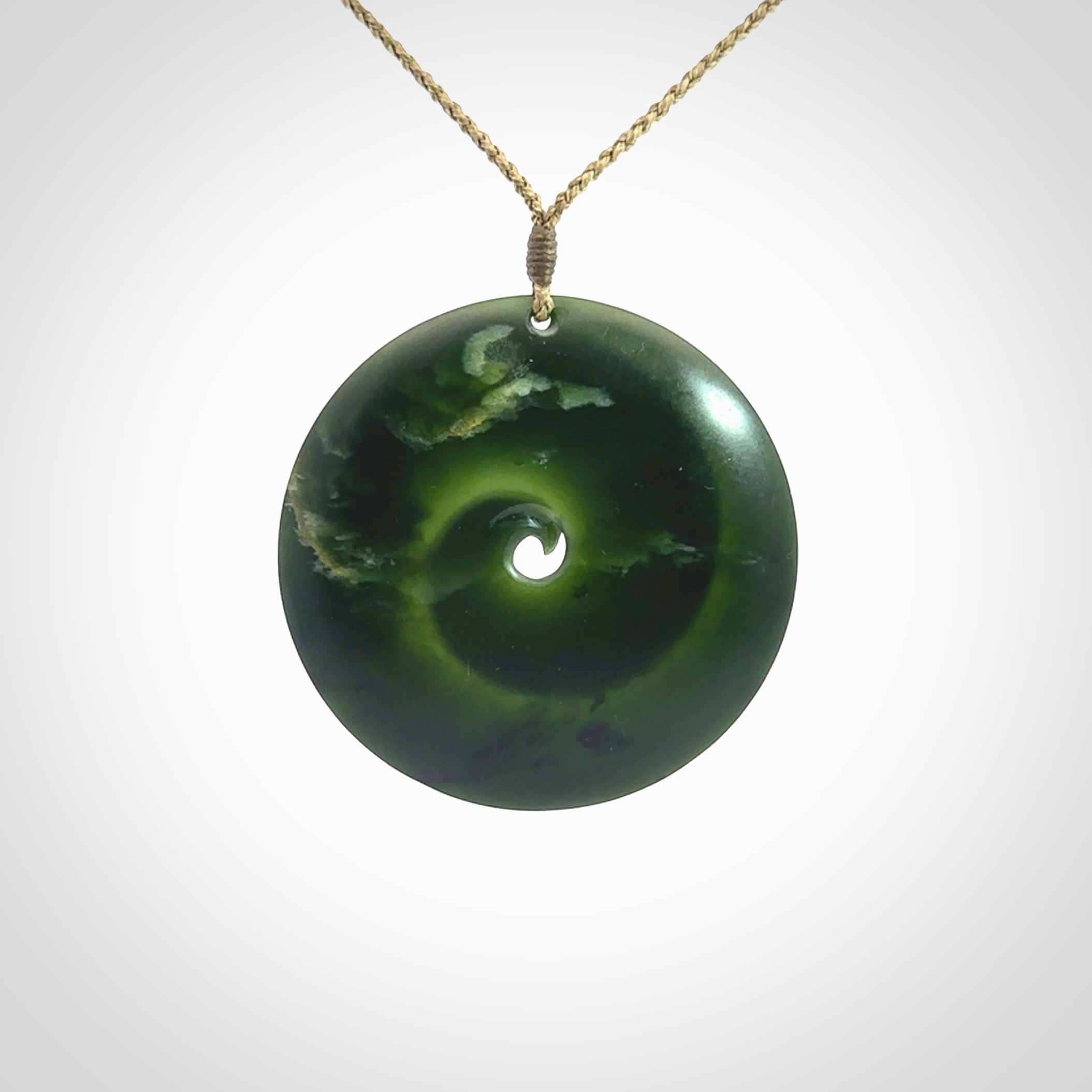 This is a large green New Zealand jade cupped koru pendant. We have bound this with a khaki coloured cord necklace. The necklace is adjustable so you can position the piece where it suits you the best. Hand made by Ric Moor.