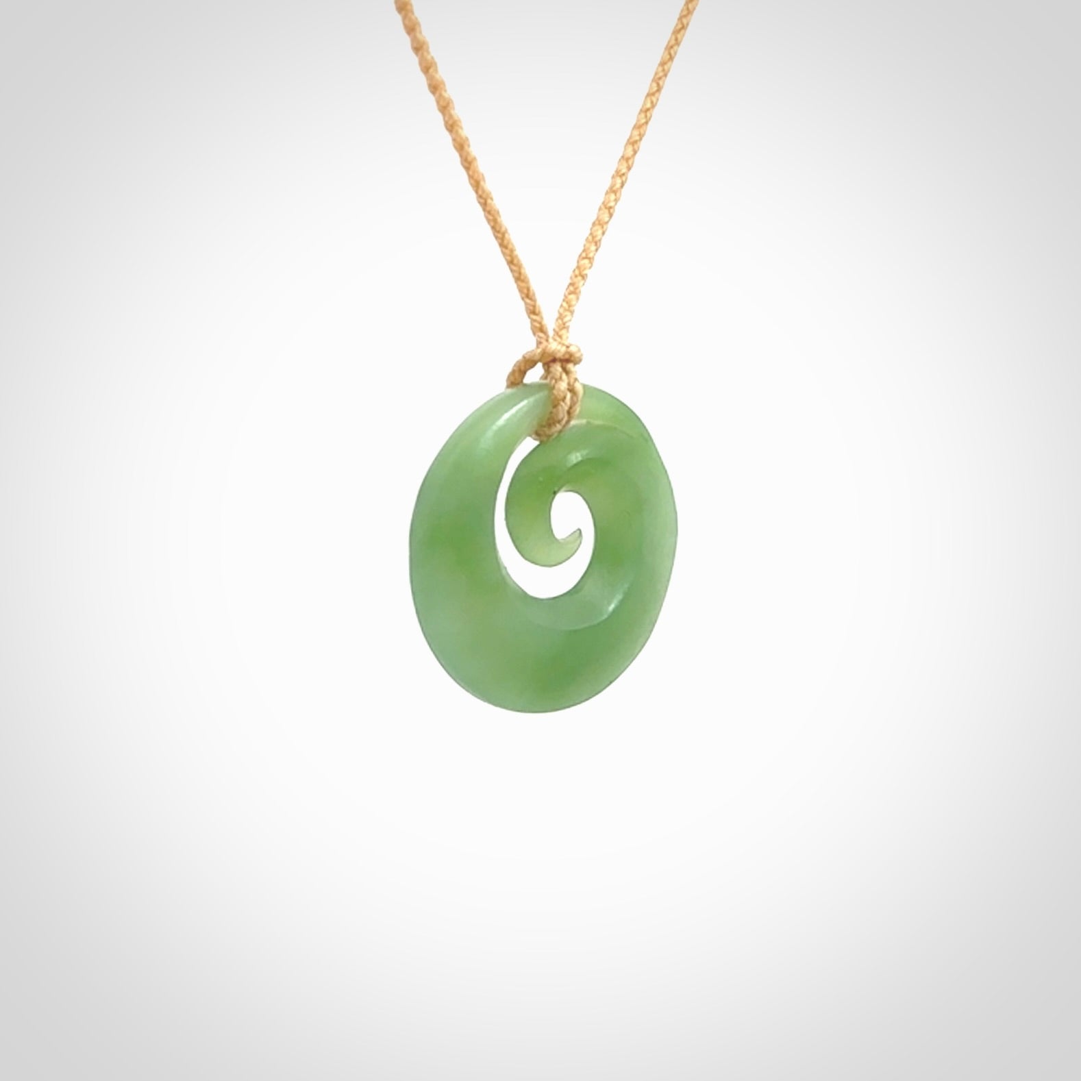 This is a small light green New Zealand jade koru pendant. We have bound this with a fine beige coloured cord necklace. The necklace is adjustable so you can position the piece where it suits you the best.