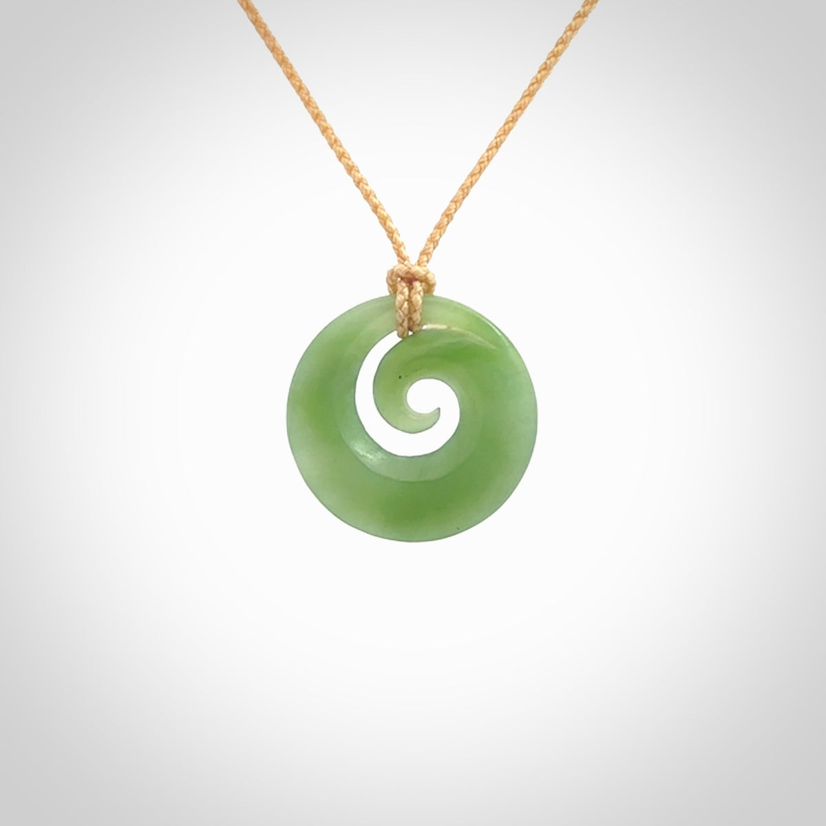 This is a small light green New Zealand jade koru pendant. We have bound this with a fine beige coloured cord necklace. The necklace is adjustable so you can position the piece where it suits you the best.