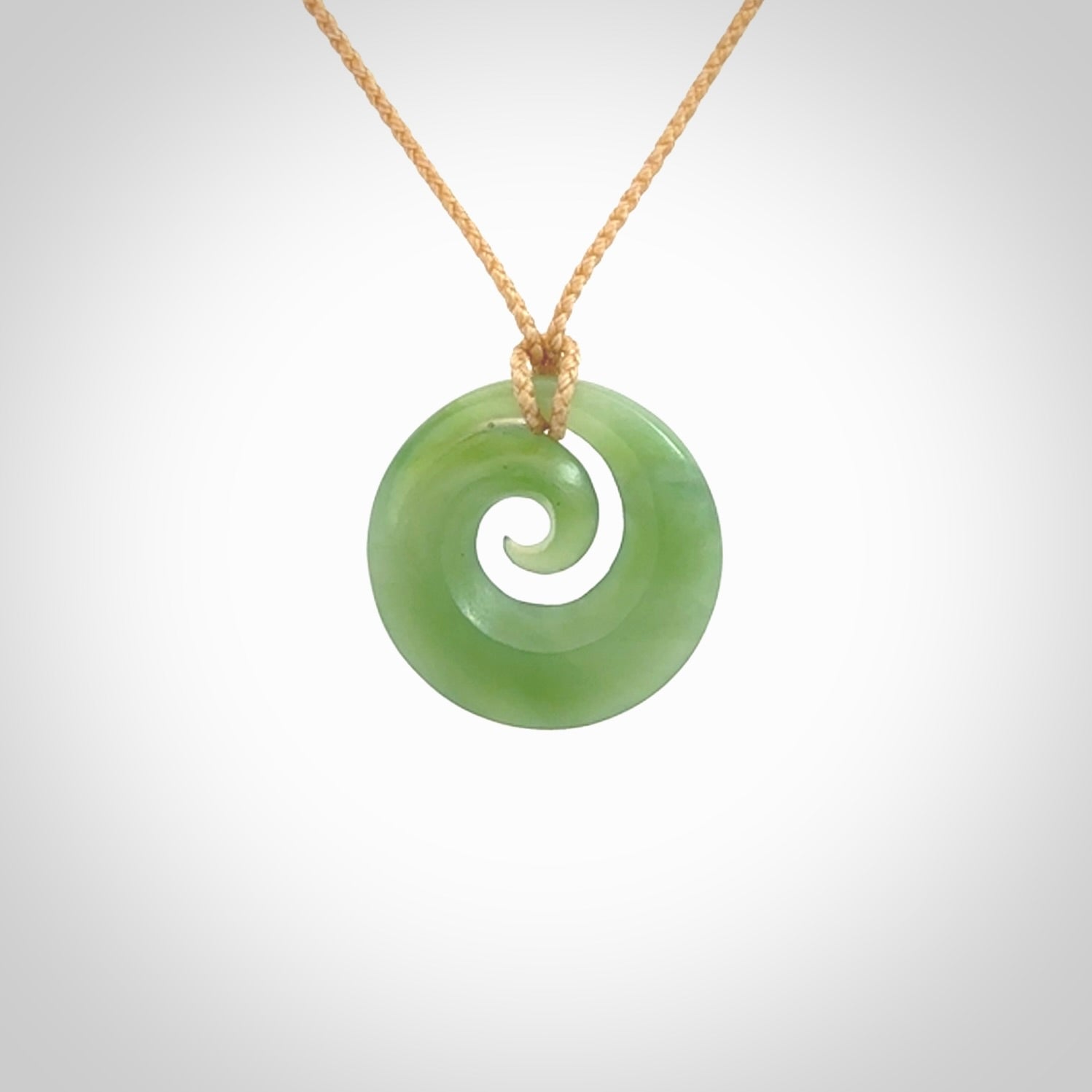 This is a small light green New Zealand jade koru pendant. We have bound this with a fine beige coloured cord necklace. The necklace is adjustable so you can position the piece where it suits you the best.