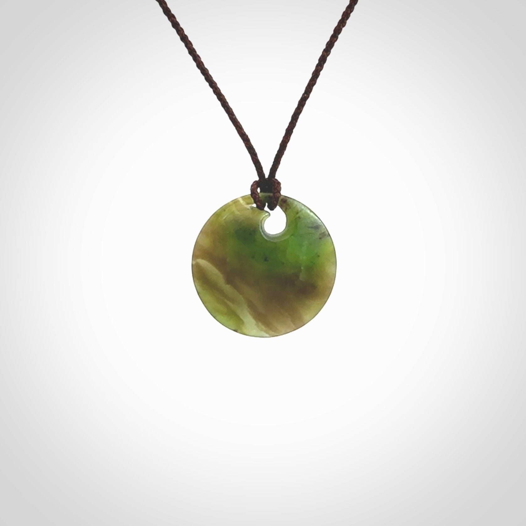 This is a small New Zealand jade koru pendant. We have bound this with a fine brown coloured cord necklace. The necklace is adjustable so you can position the piece where it suits you the best. Hand made by Ric Moor.