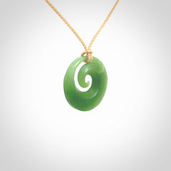 This is a small light green New Zealand Inanga jade koru pendant. We have bound this with a fine beige coloured cord necklace. The necklace is adjustable so you can position the piece where it suits you the best.